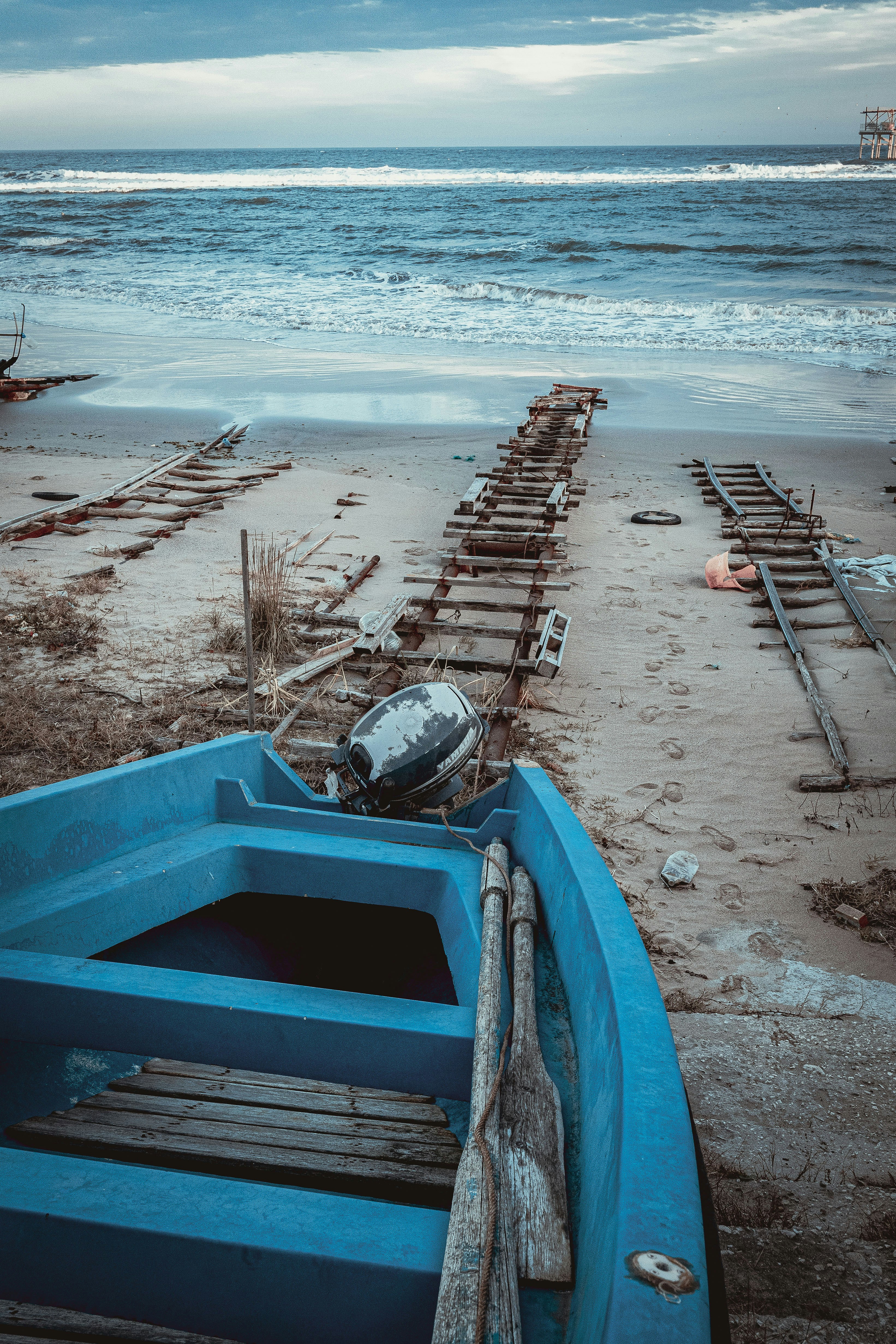 Blaues Boot mit Rudern an einem Sandstrand mit Ketten.