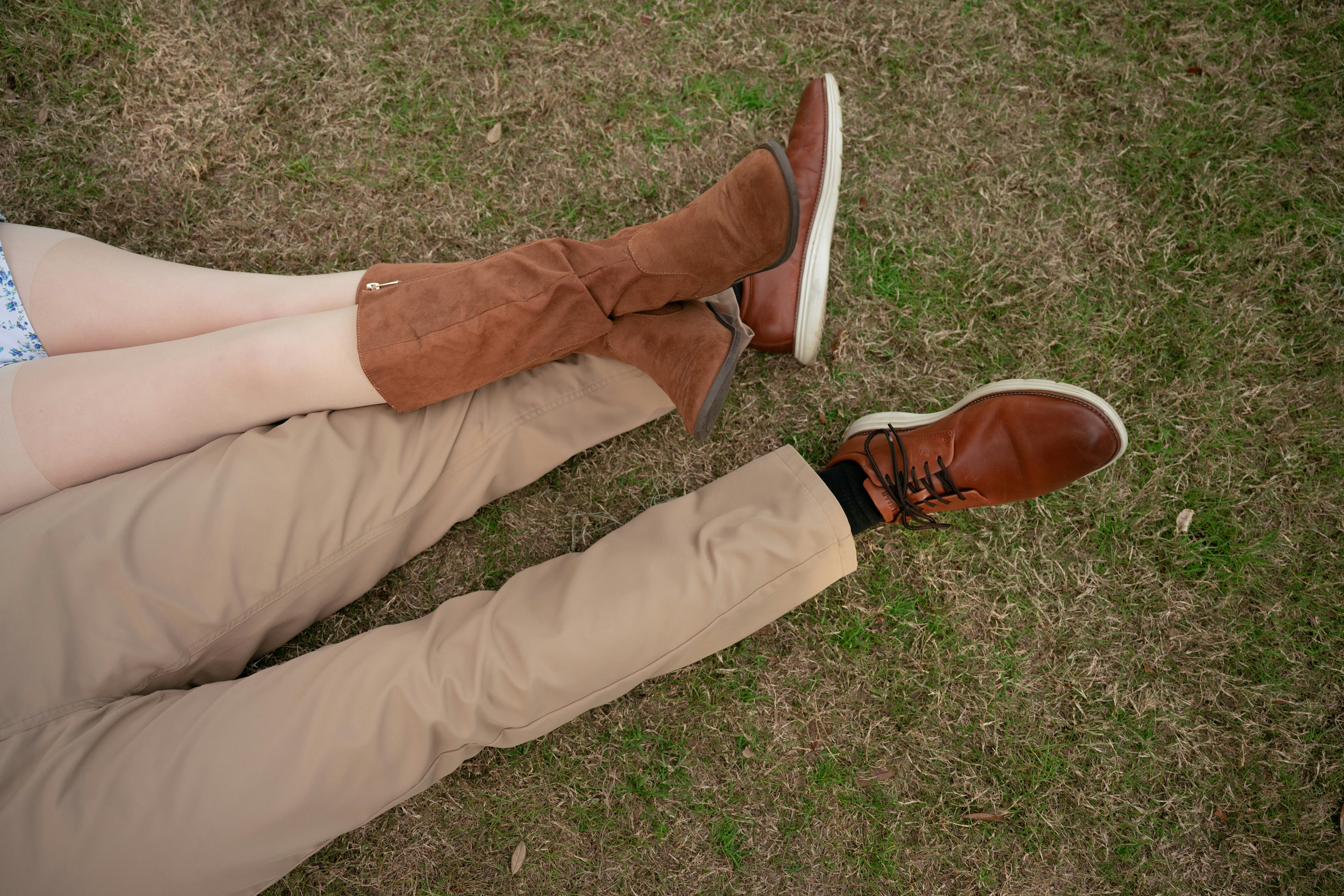 Two people lying on grass with legs crossed