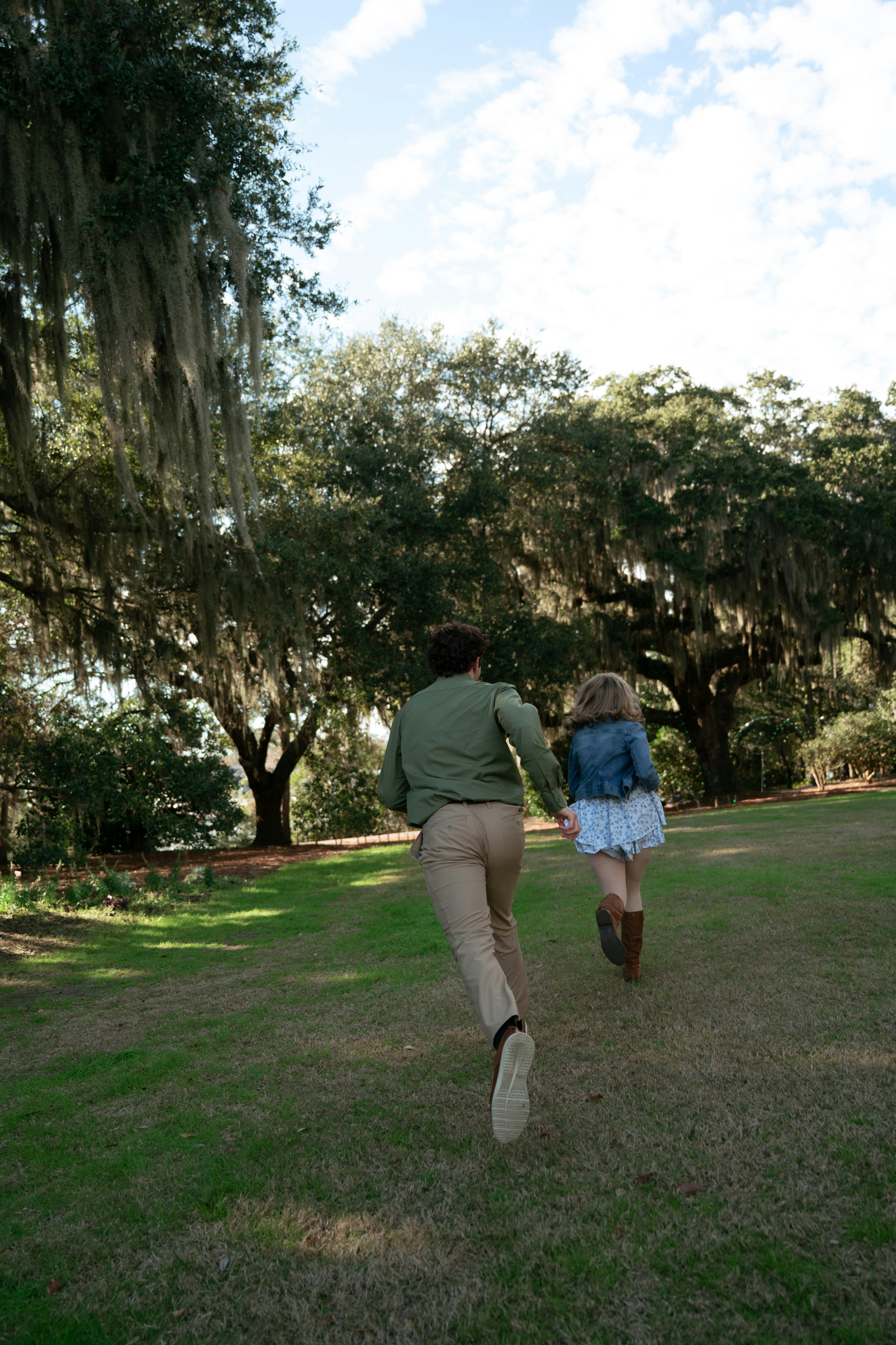 Pareja corriendo por un parque de césped con árboles.