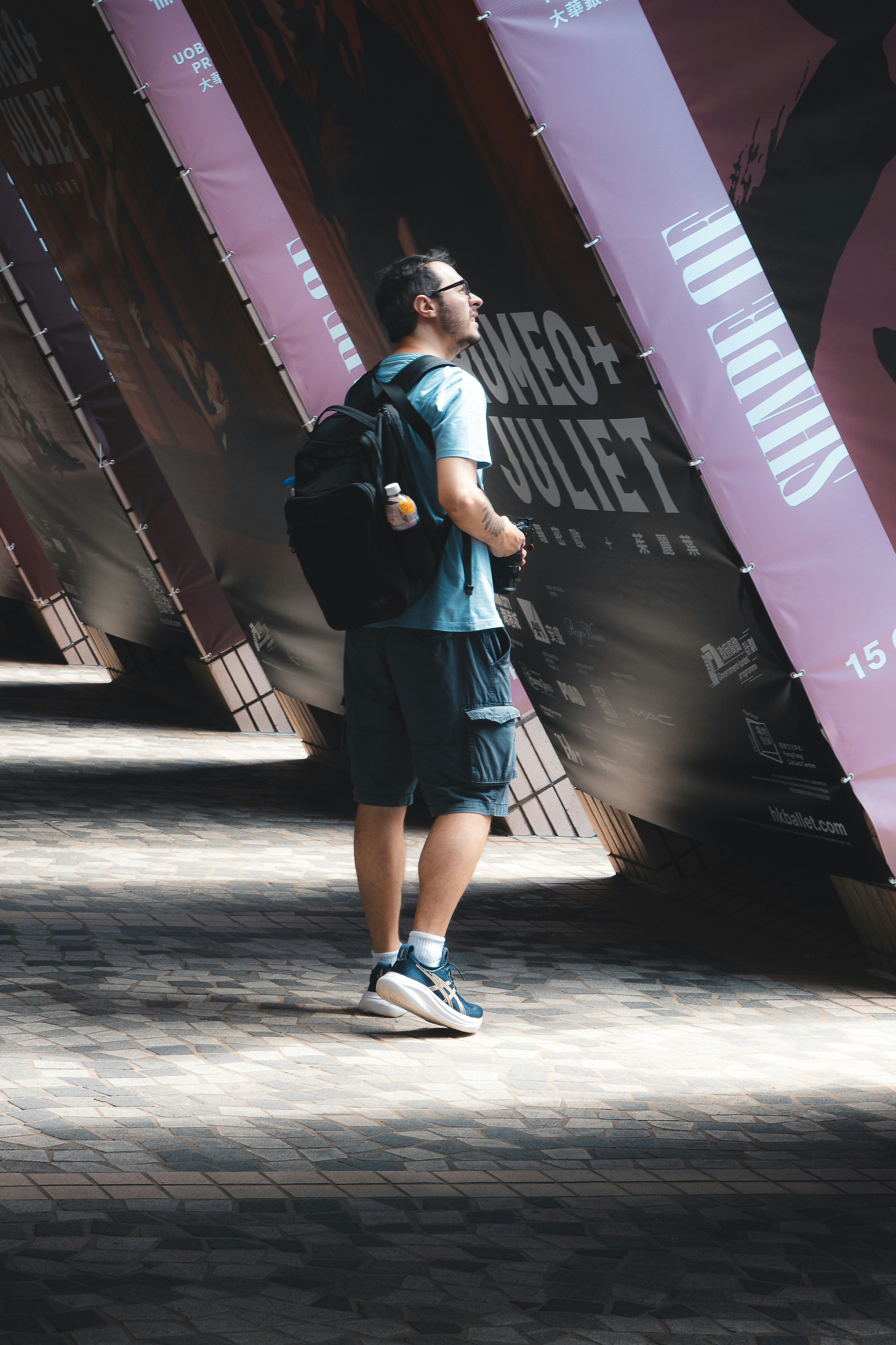 Man with backpack looking up at banners