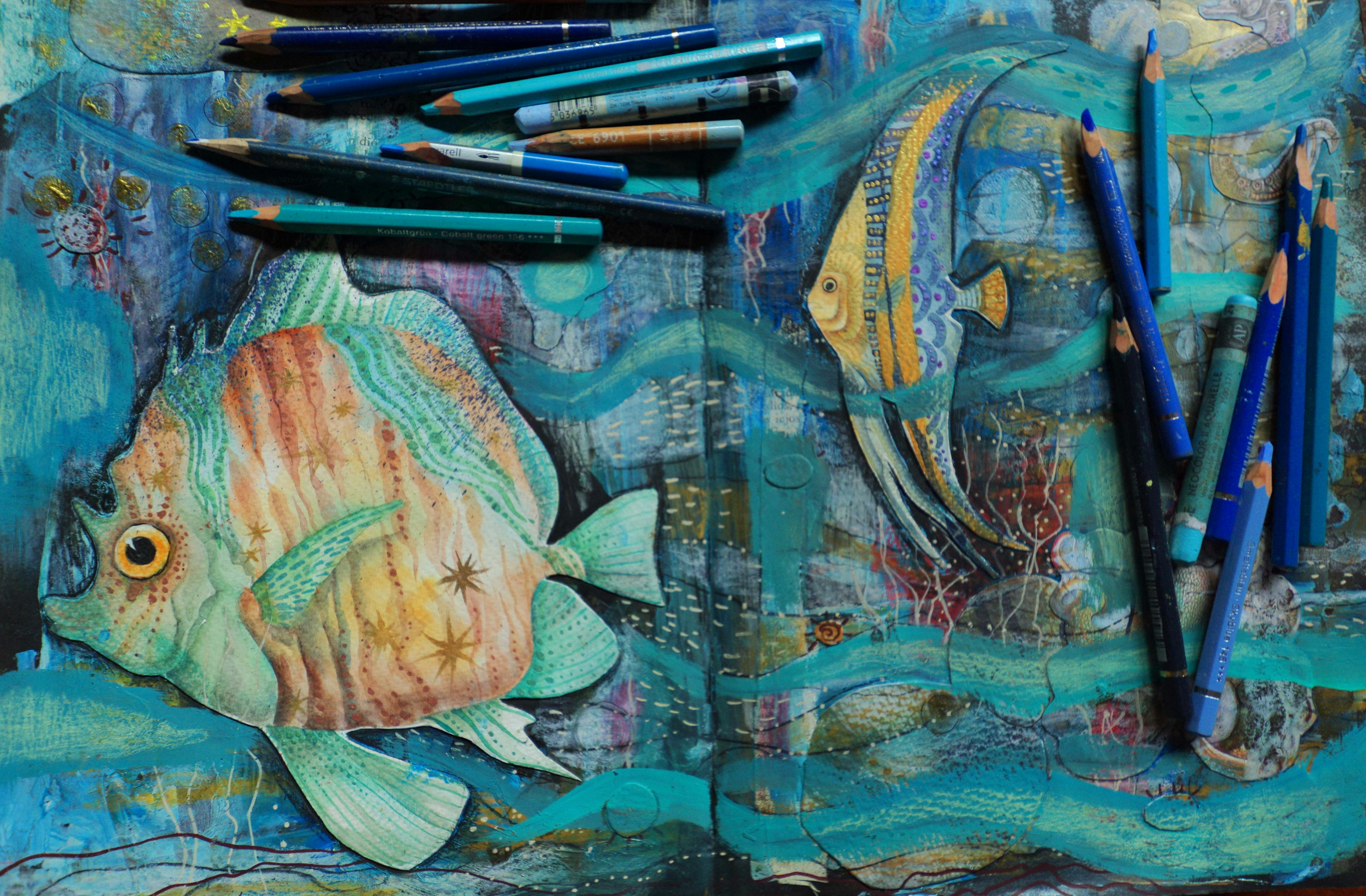 Colored pencils and artwork of tropical fish underwater.