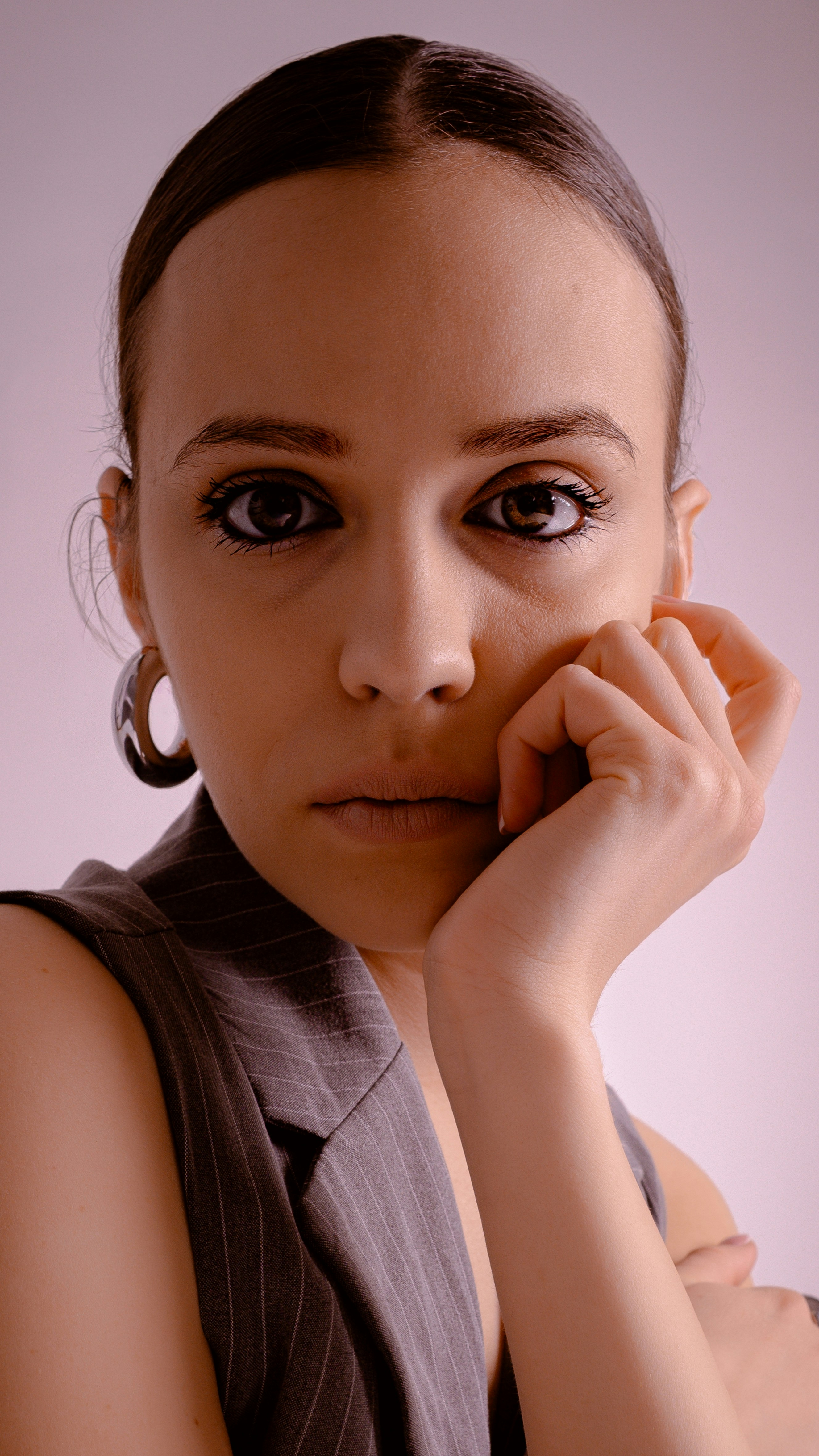 Woman in vest with hand on chin looking forward
