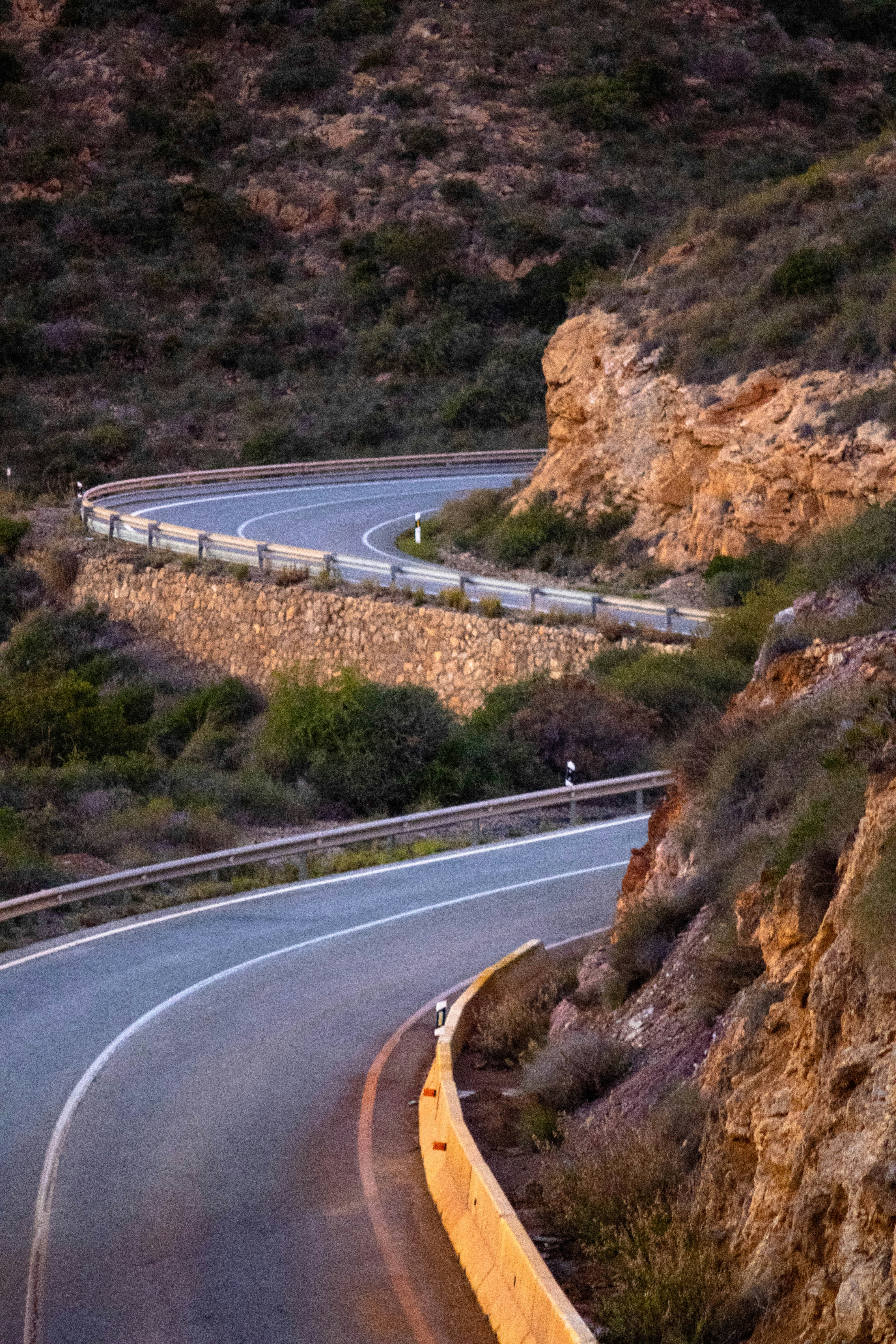 A winding road curves through a rocky, arid landscape.