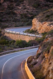A winding road curves through a rocky, arid landscape.