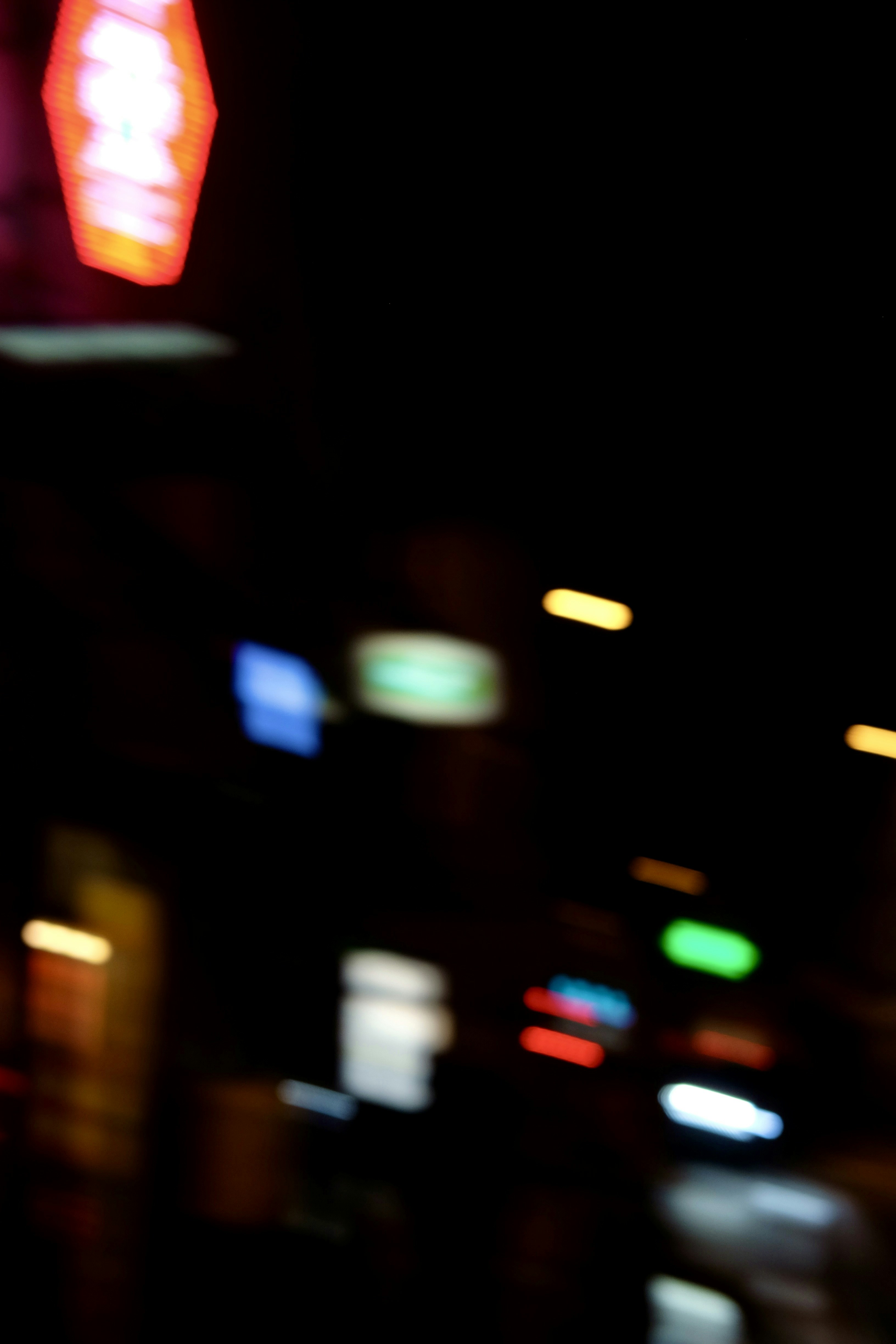 Blurry city lights at night with neon signs.