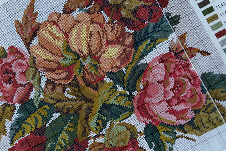 Close-up of a floral cross-stitch on Aida with a color chart