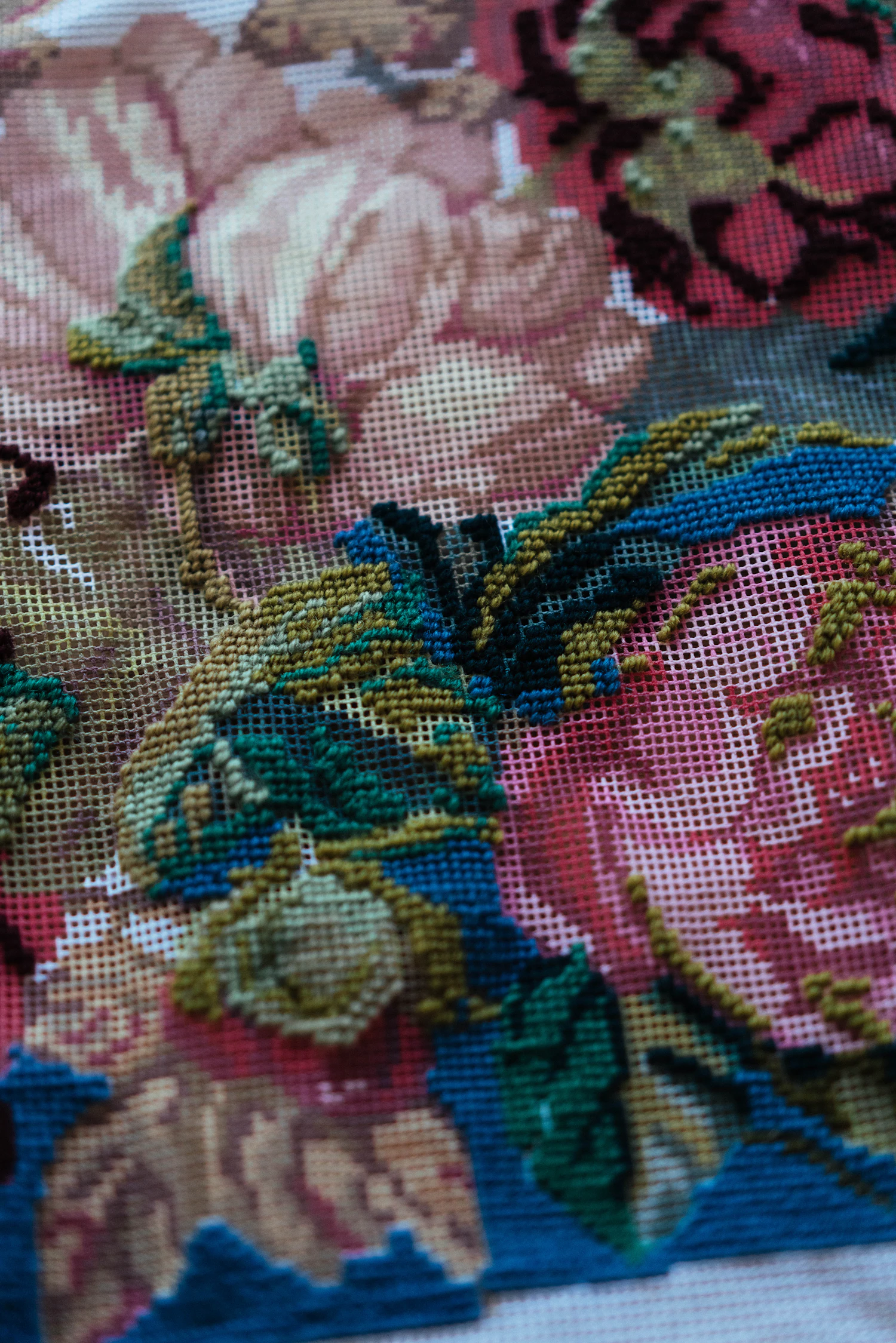 A close view of floral needlepoint in magenta, green and blue wool
