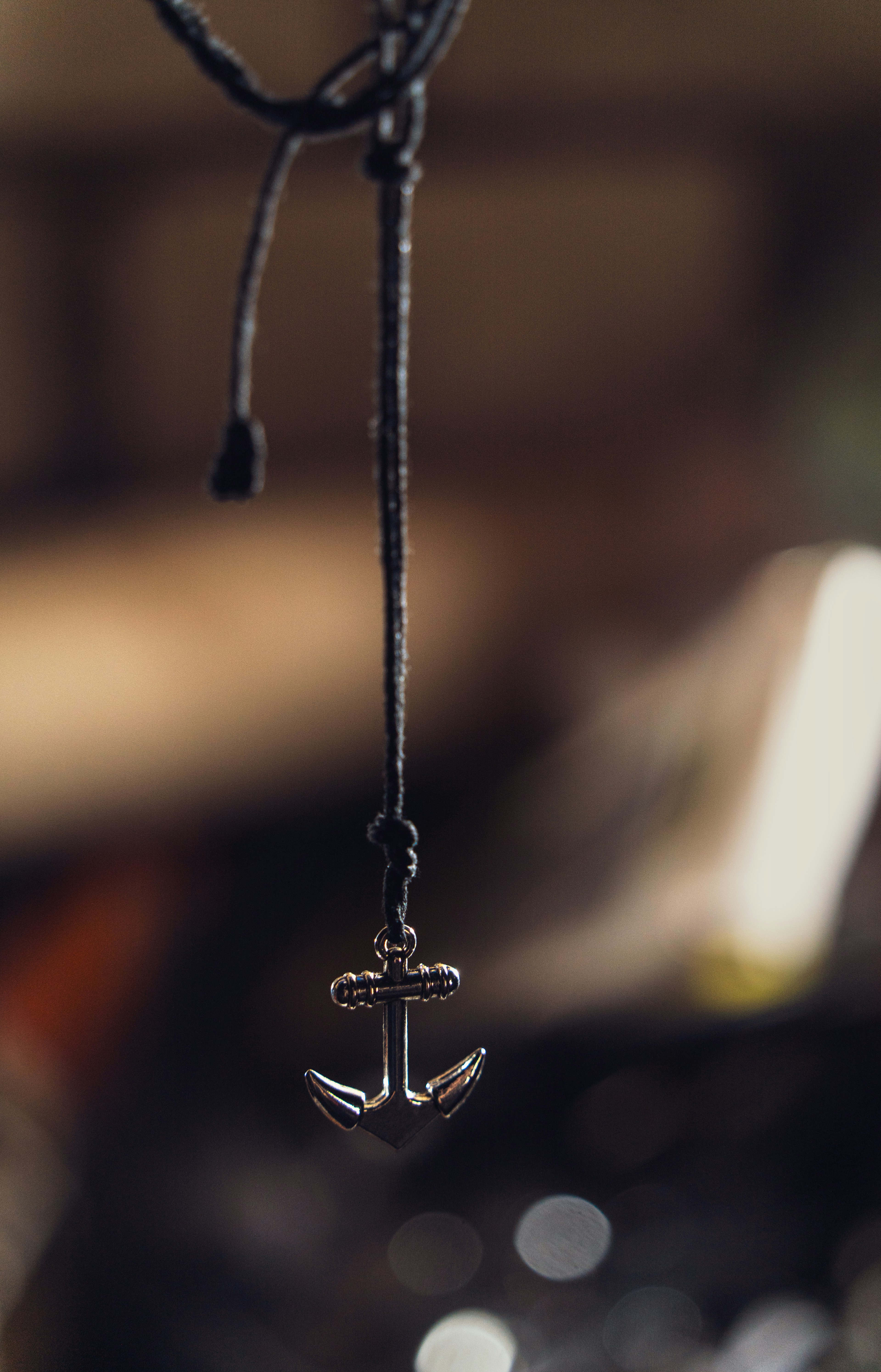 暗い紐に吊るされた銀の錨のペンダント