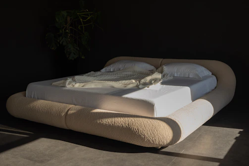 Modern bed with rounded headboard and white linens.