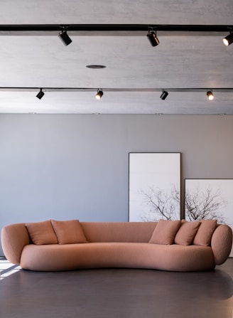 A modern peach sofa with pillows in a room.