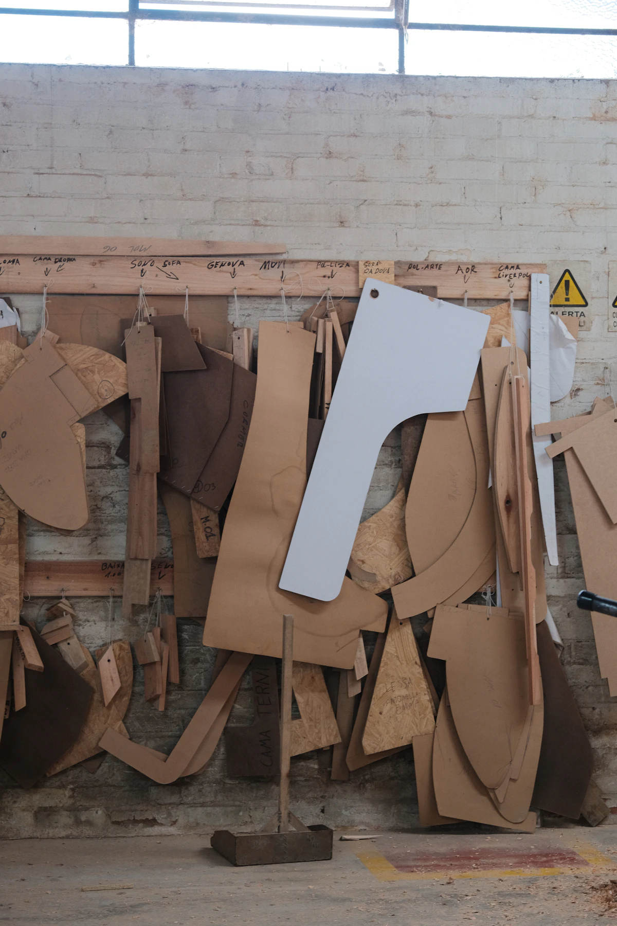 Op maat gesneden leren patronen hangen in een atelier, gebruikt om zooltjes te vormen.