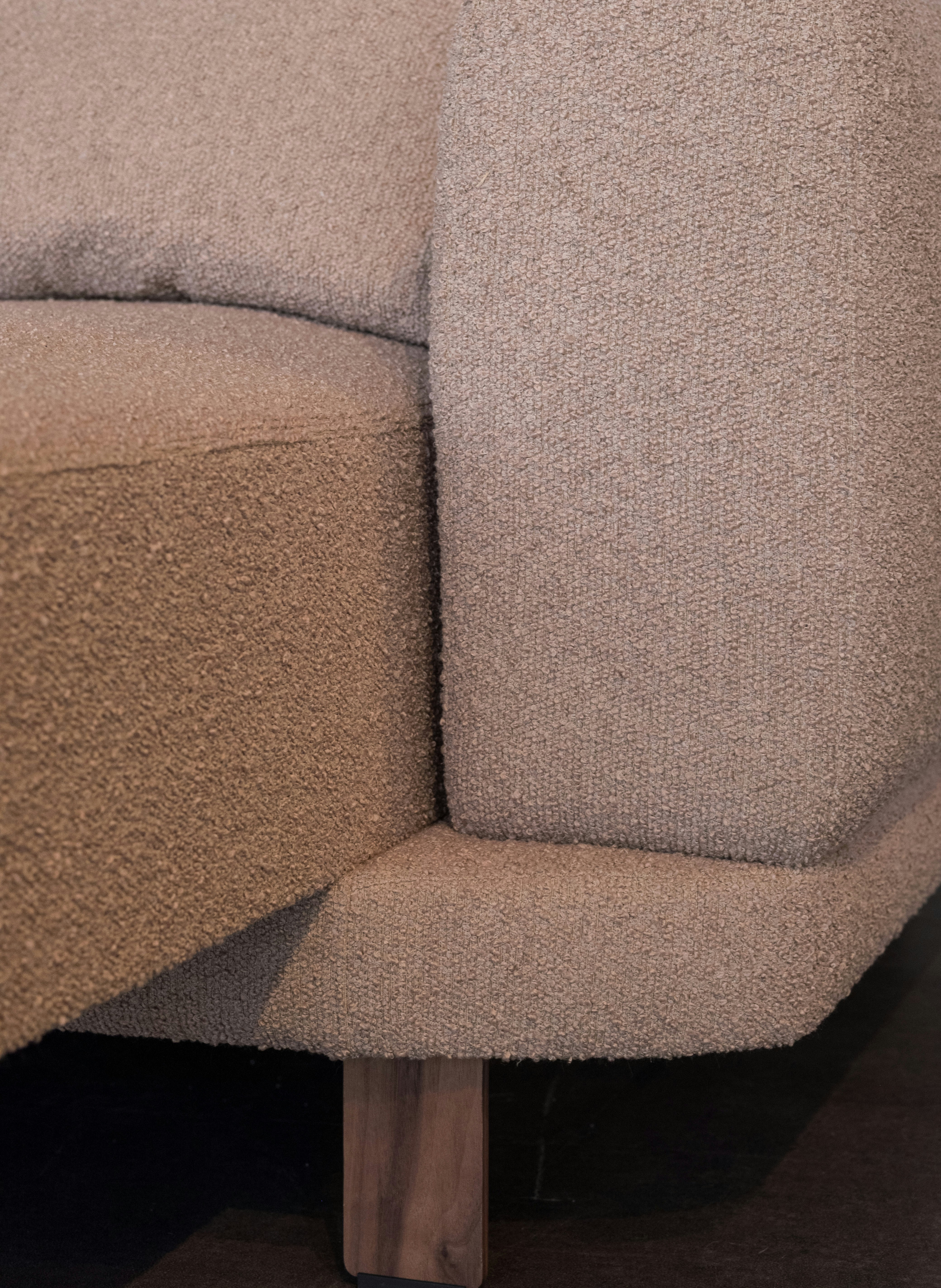 Close-up of a textured beige sofa with wooden legs
