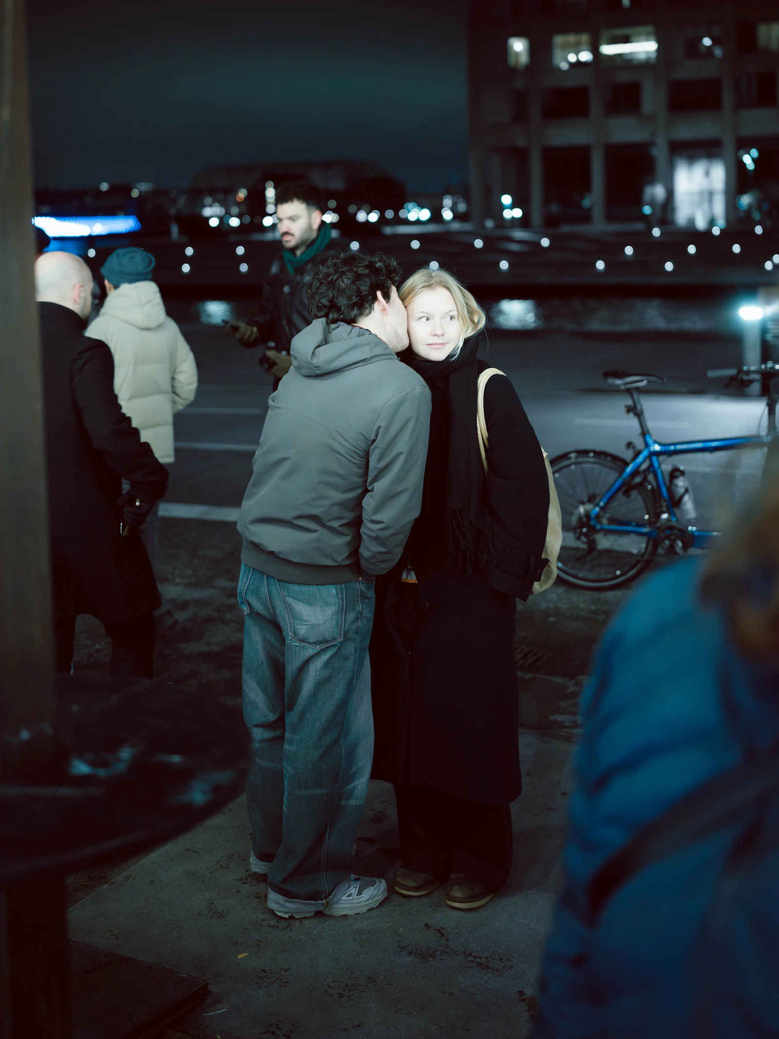 Man whispering to a woman on a city street at night
