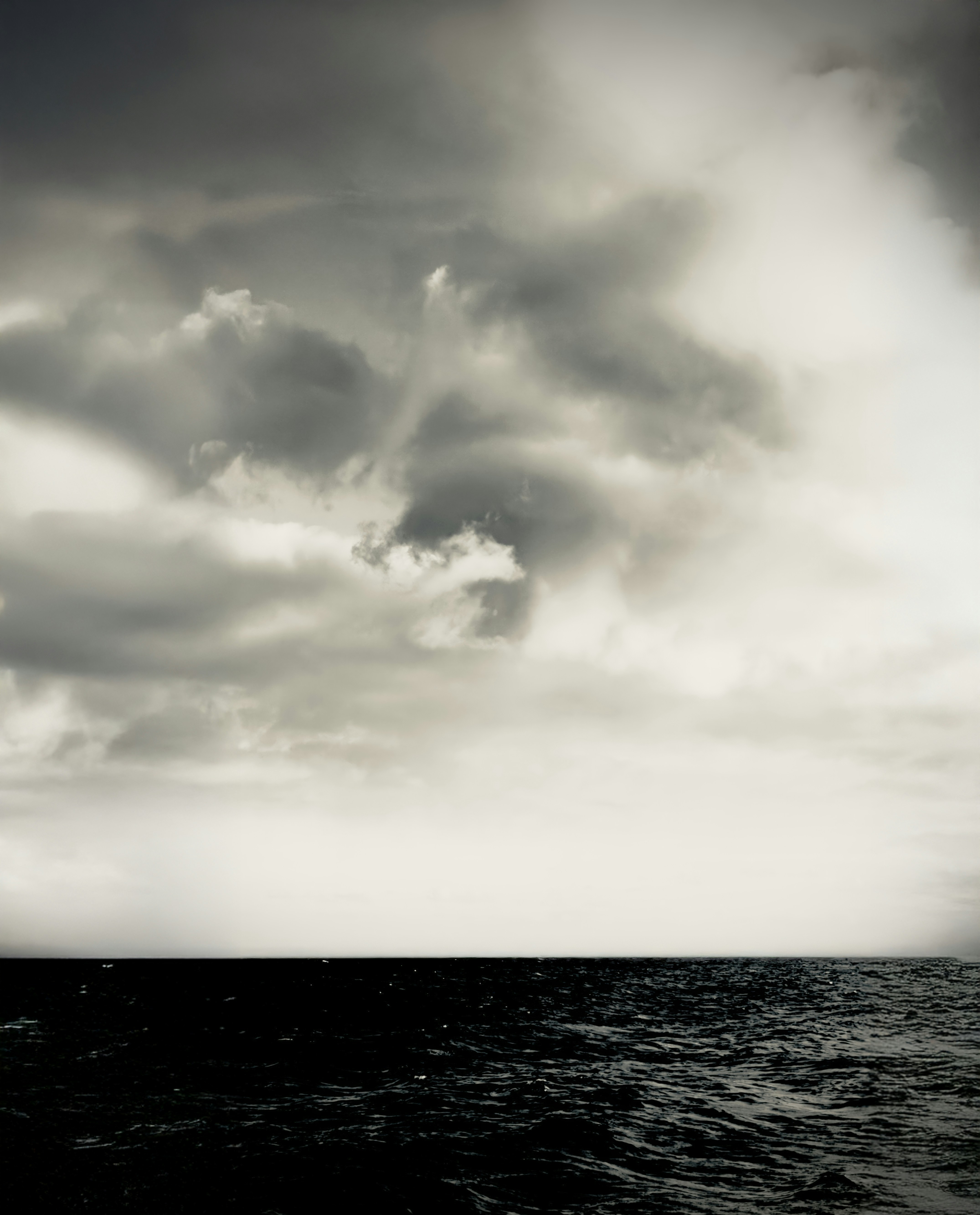 Nuvole scure e drammatiche su un oceano turbolento.