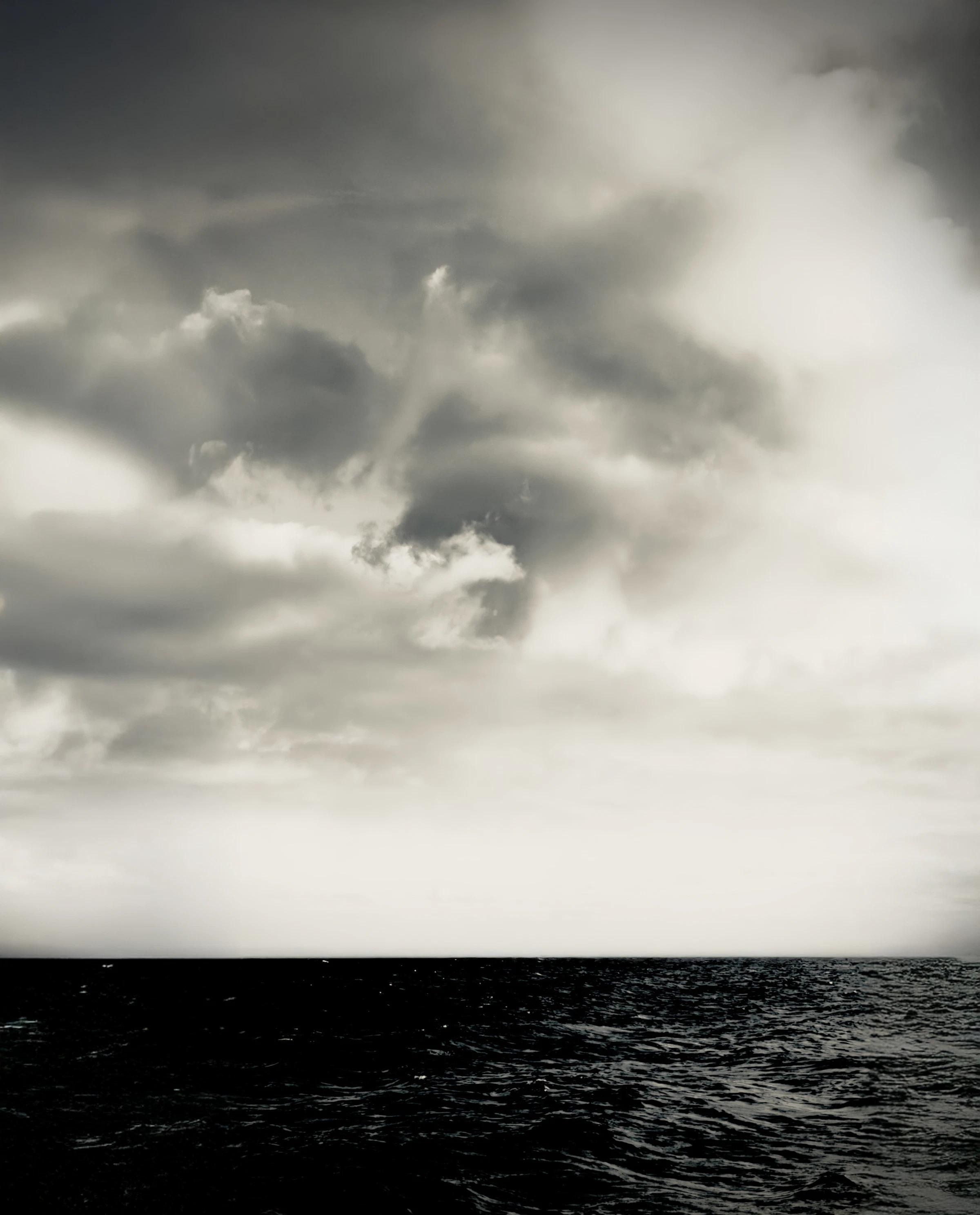 Dark, dramatic clouds banked over a turbulent open ocean