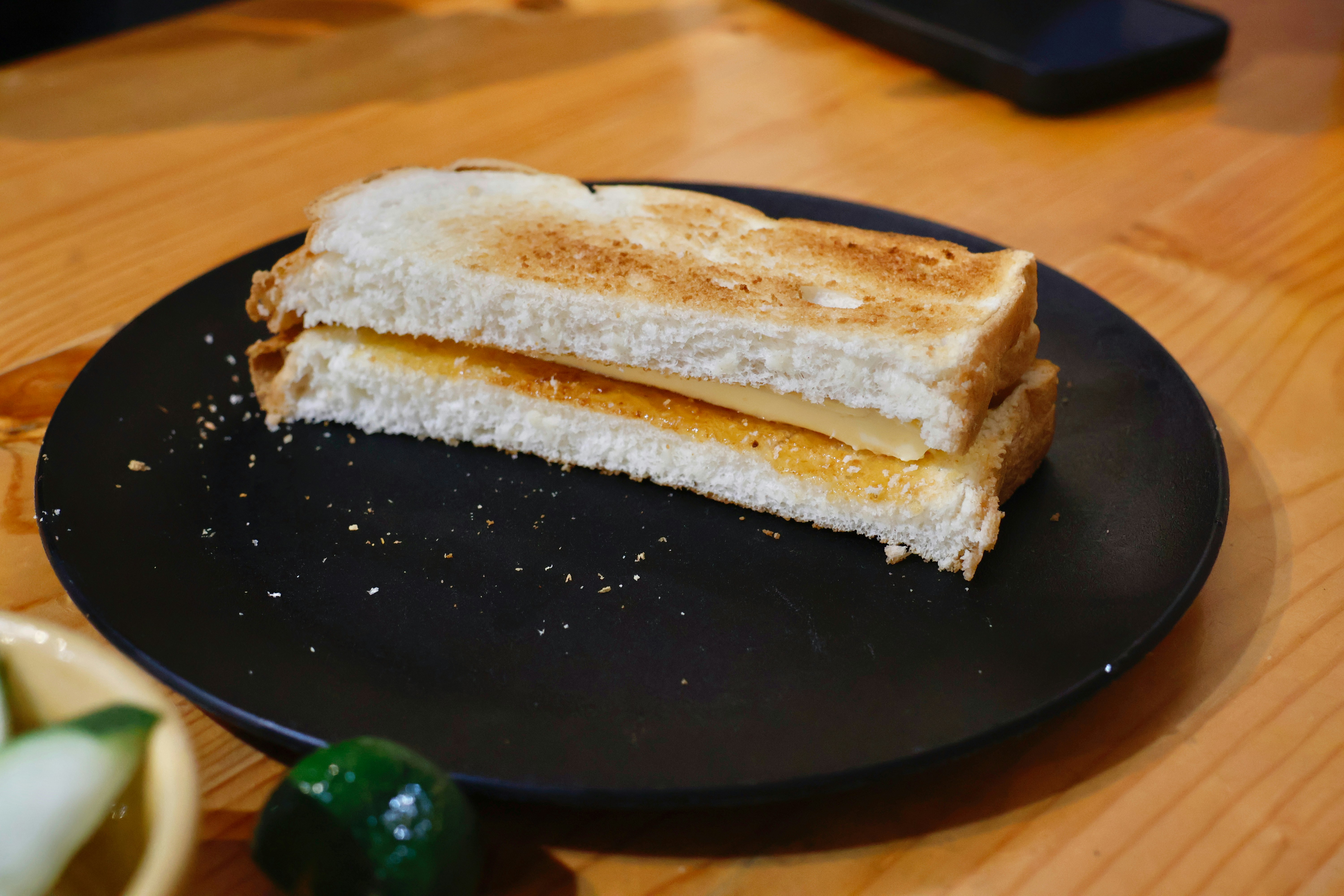Toasted cheese sandwich on a black plate.