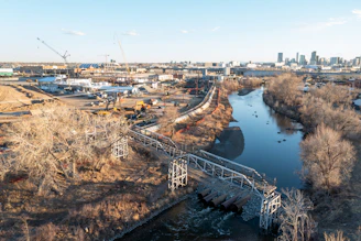 An elevated walkway crosses a river near an industrial area.