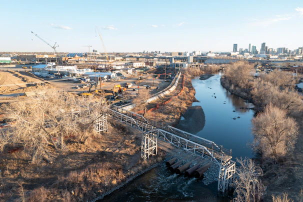 An elevated walkway crosses a river near an industrial area.