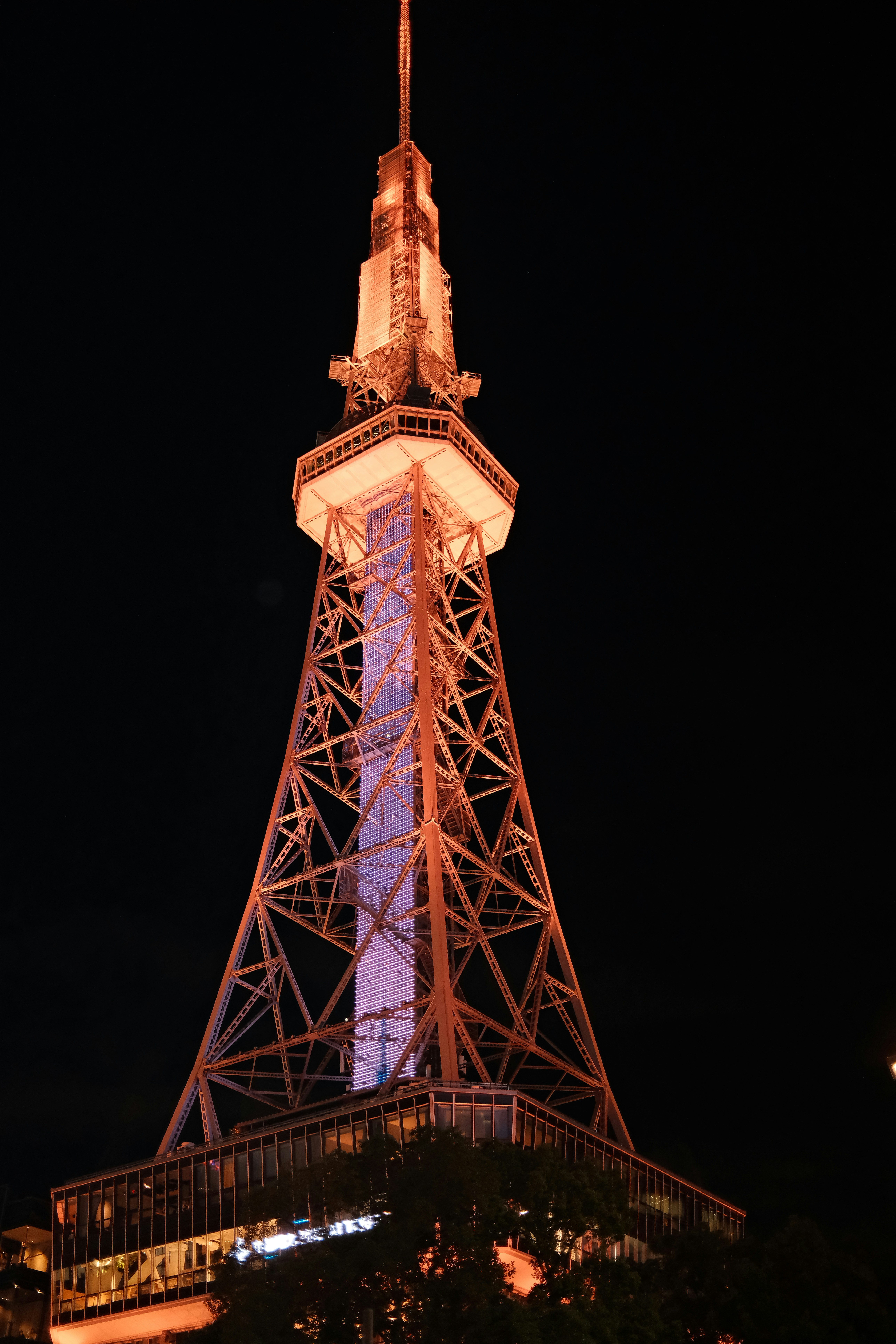 Illuminated radio tower at night against dark sky.
