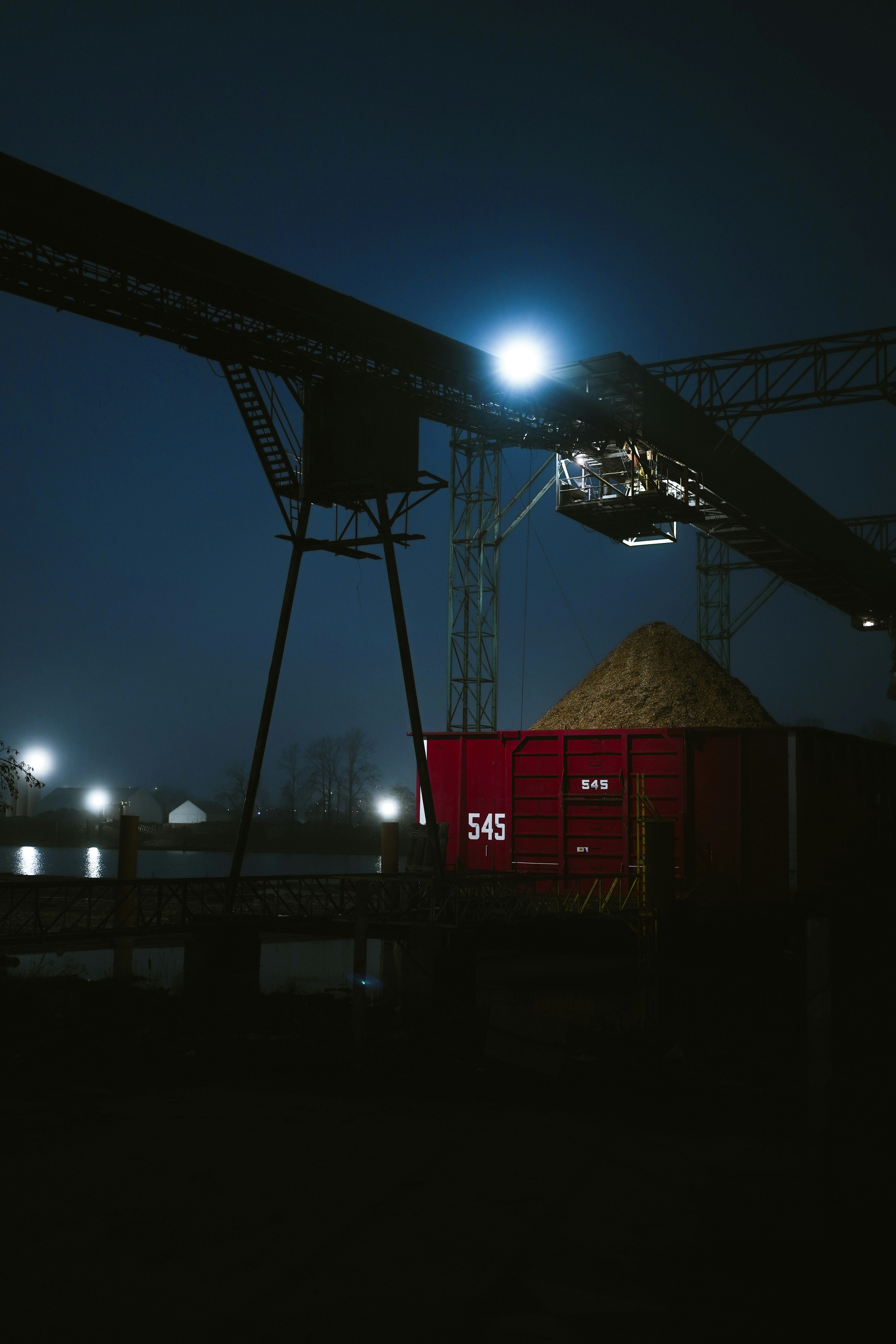 Red train car filled with sand at night