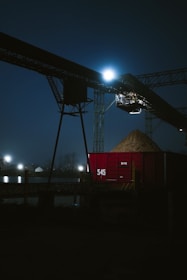Red train car filled with sand at night