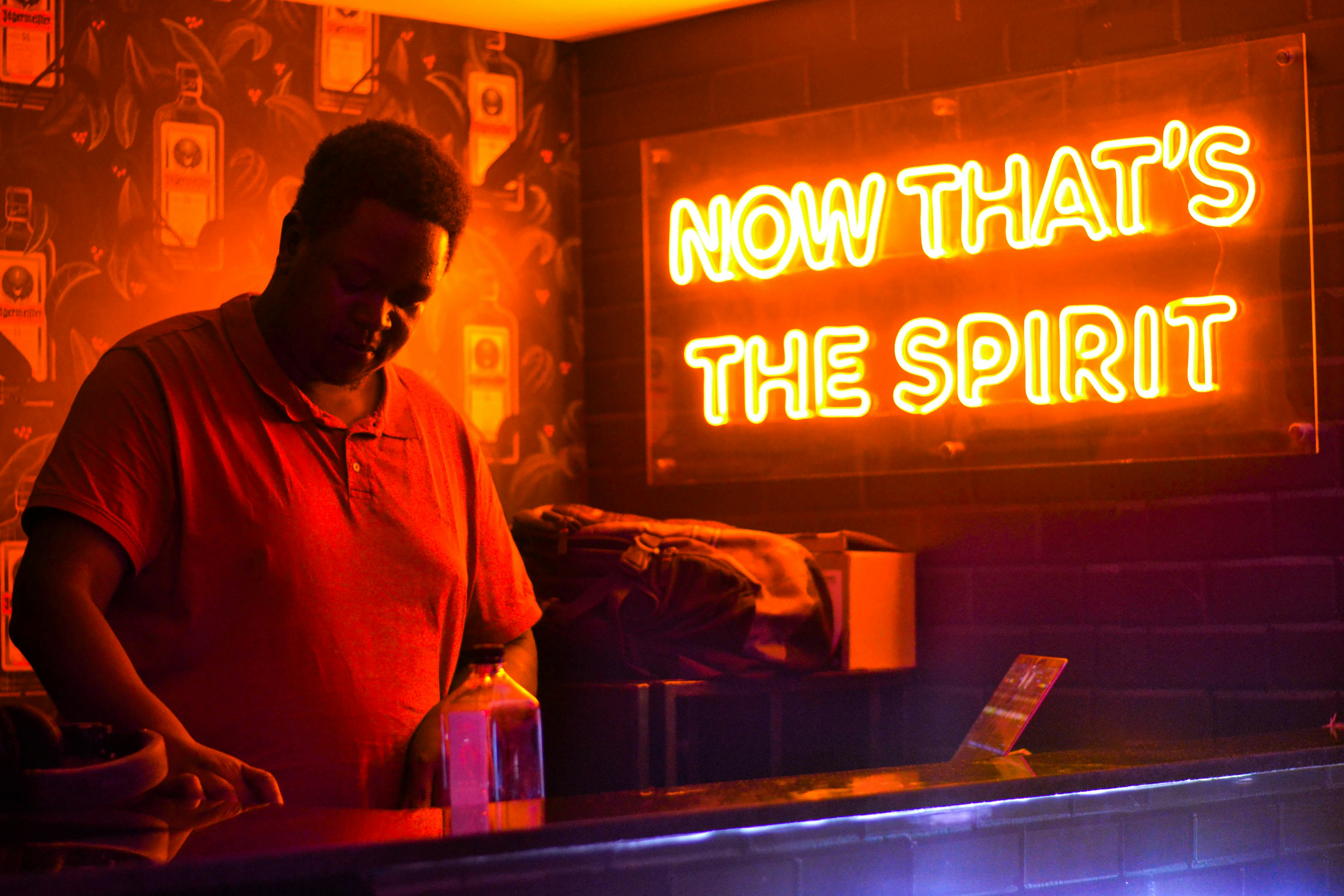 Man behind bar with neon sign