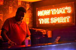 Man behind bar with neon sign