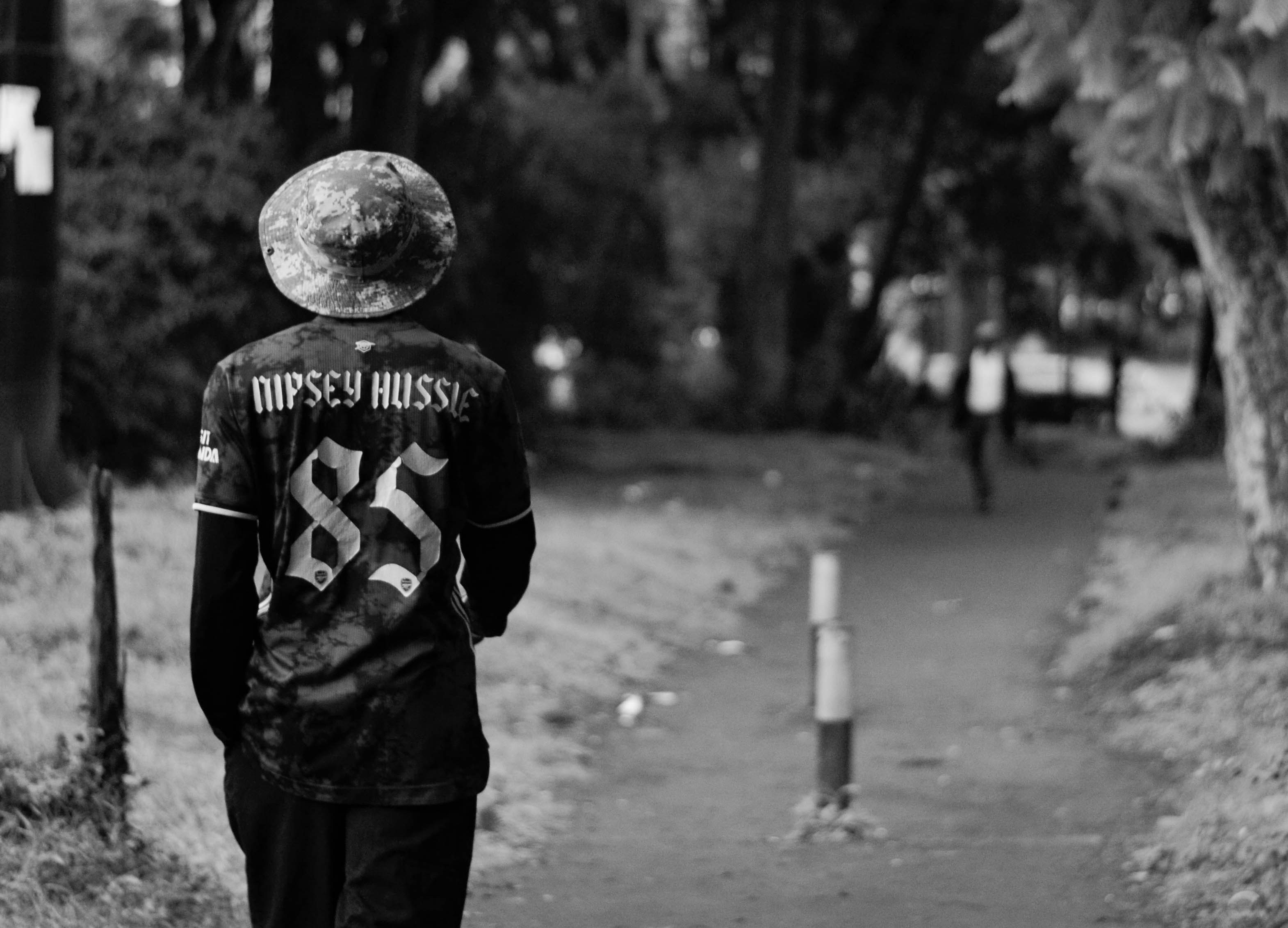 Person in a baseball jersey walks on a path.