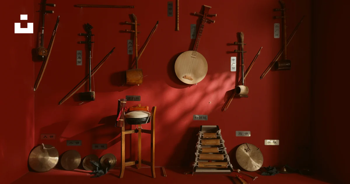 String Drum Instruments Collection of traditional string and percussion instruments on red wall ...