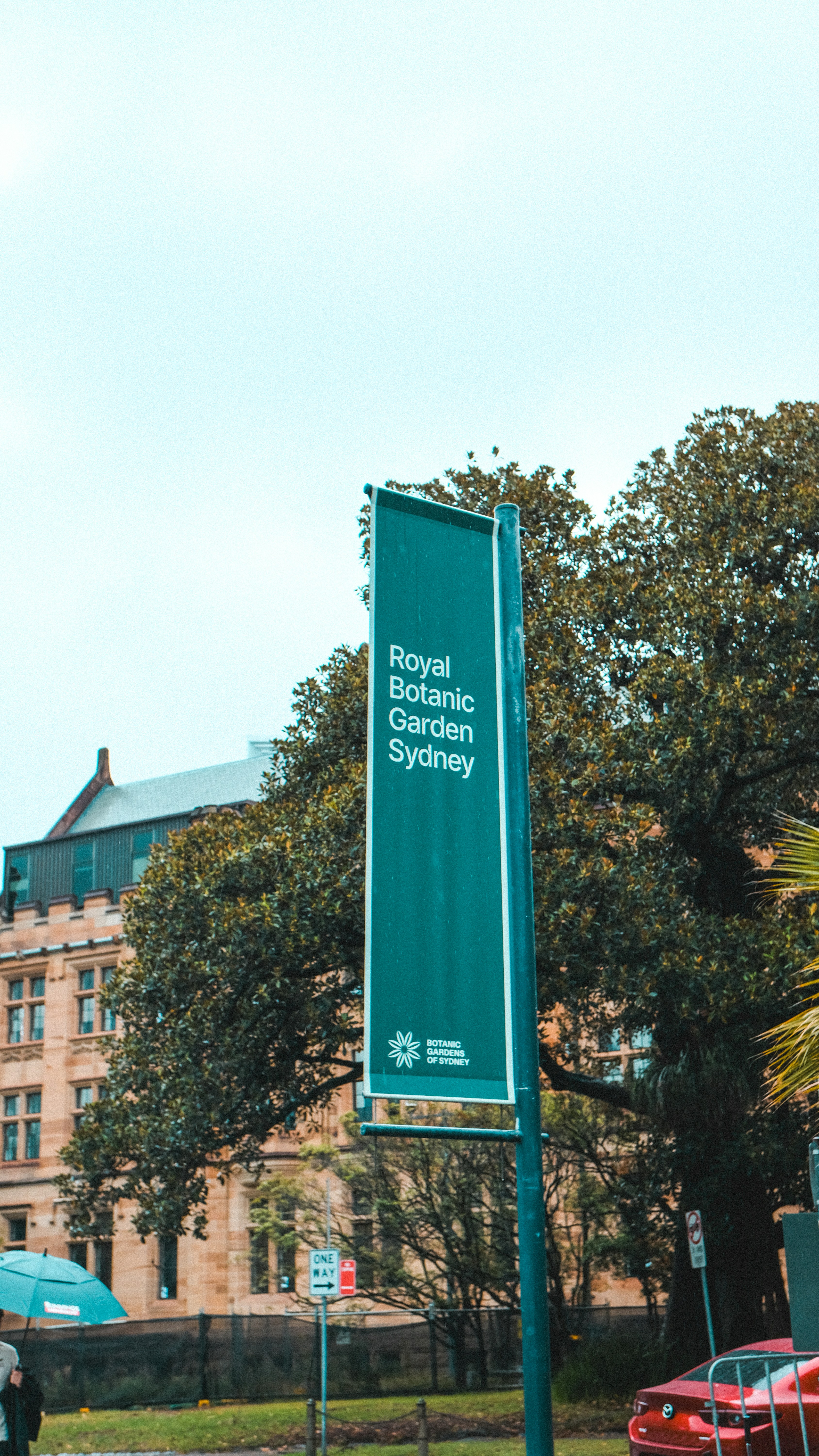 Cartel del Jardín Botánico Real de Sídney con edificio y árboles