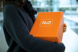 Woman holding an orange temu package