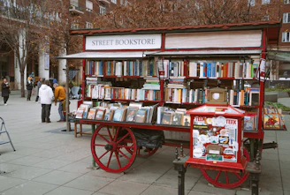 A red street bookstore cart filled with books.