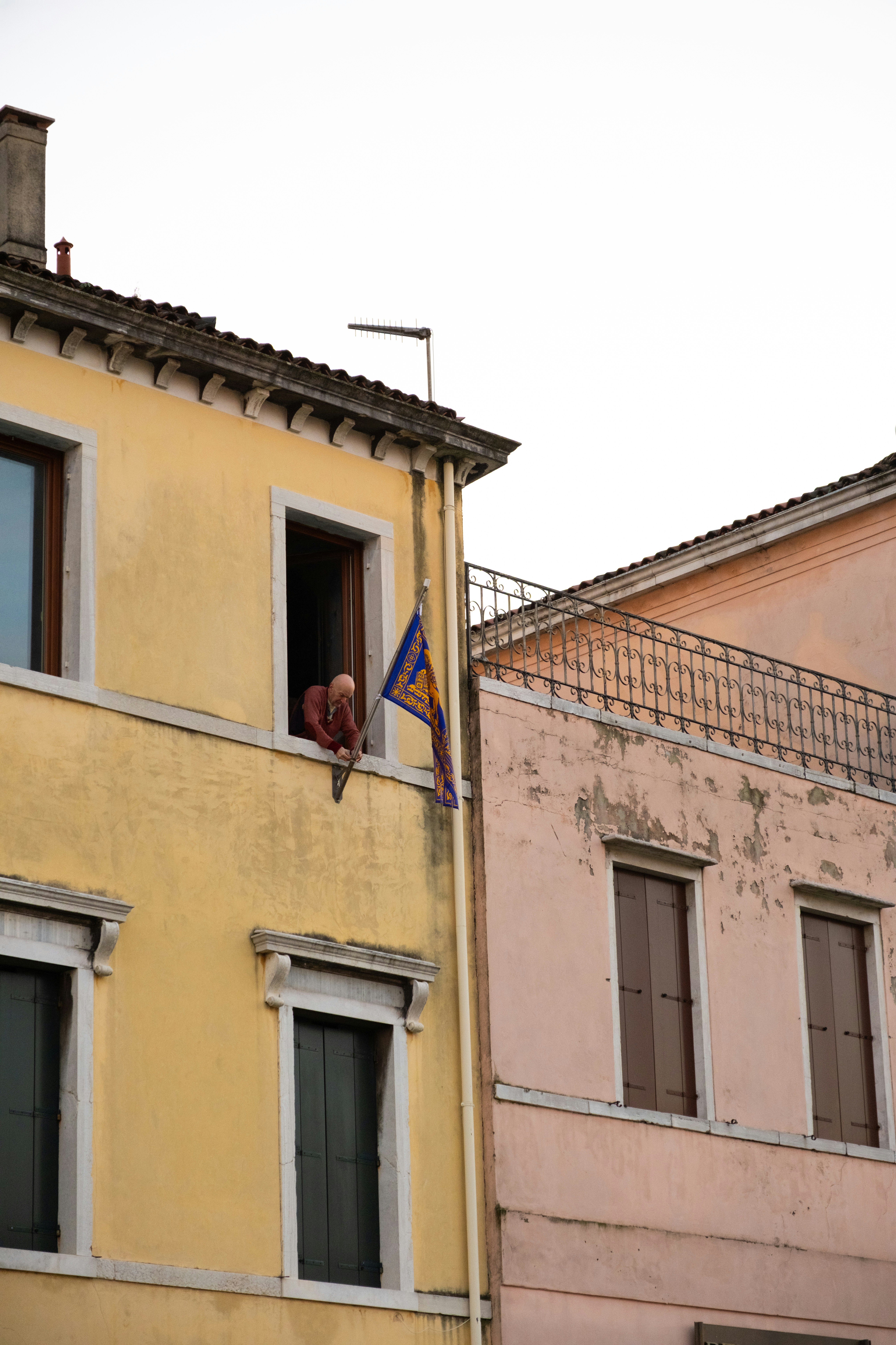 Persona sporsa fuori da una finestra gialla di un edificio.