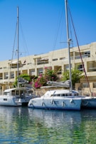 Two white sailboats docked near a building.