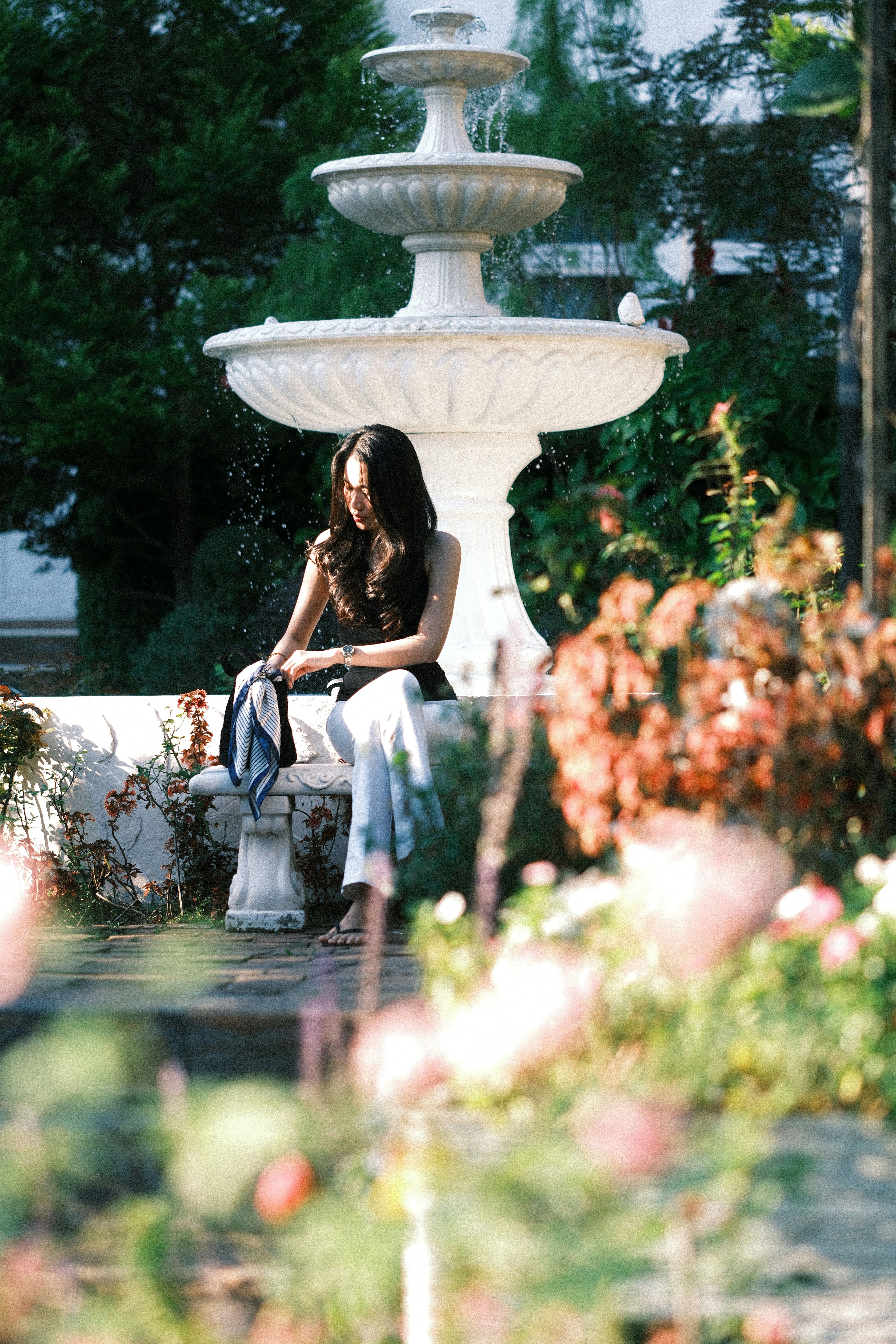Eine Frau sitzt auf einer Bank in der Nähe eines Brunnens.