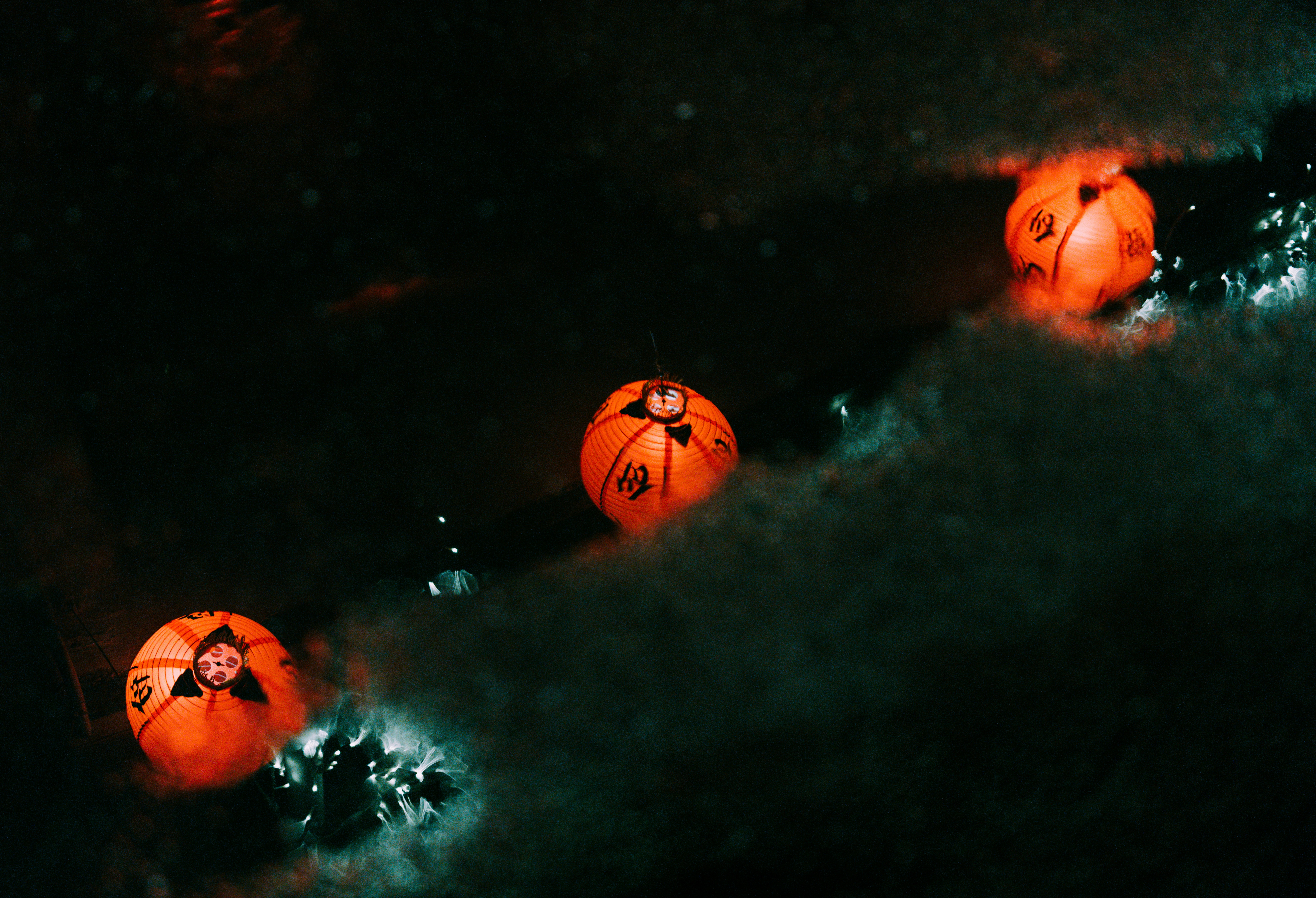 Three glowing orange lanterns float on dark water.