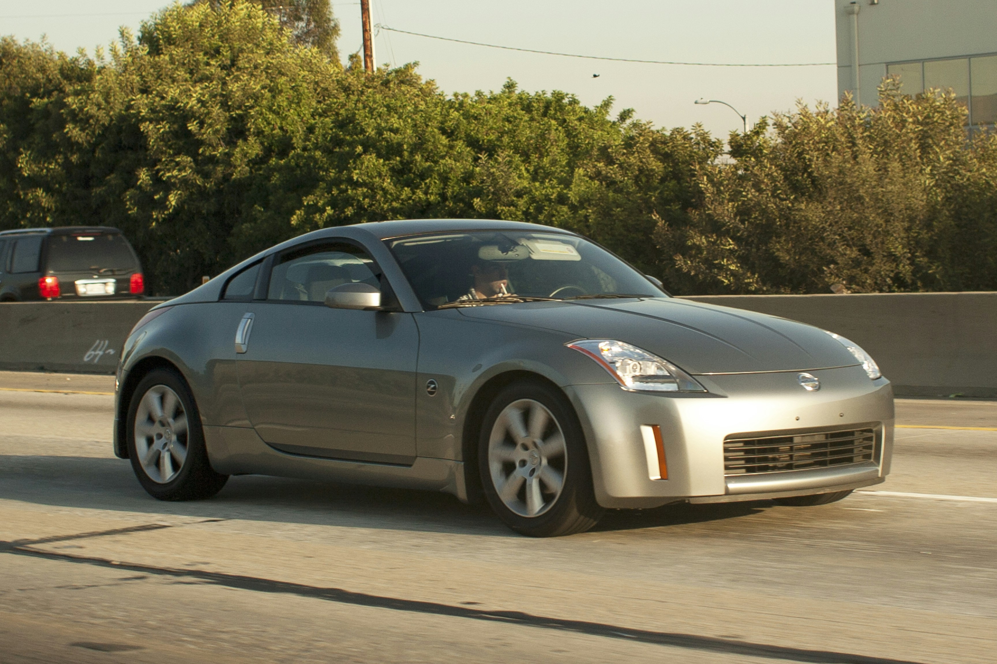 A silver sports car driving on a highway.