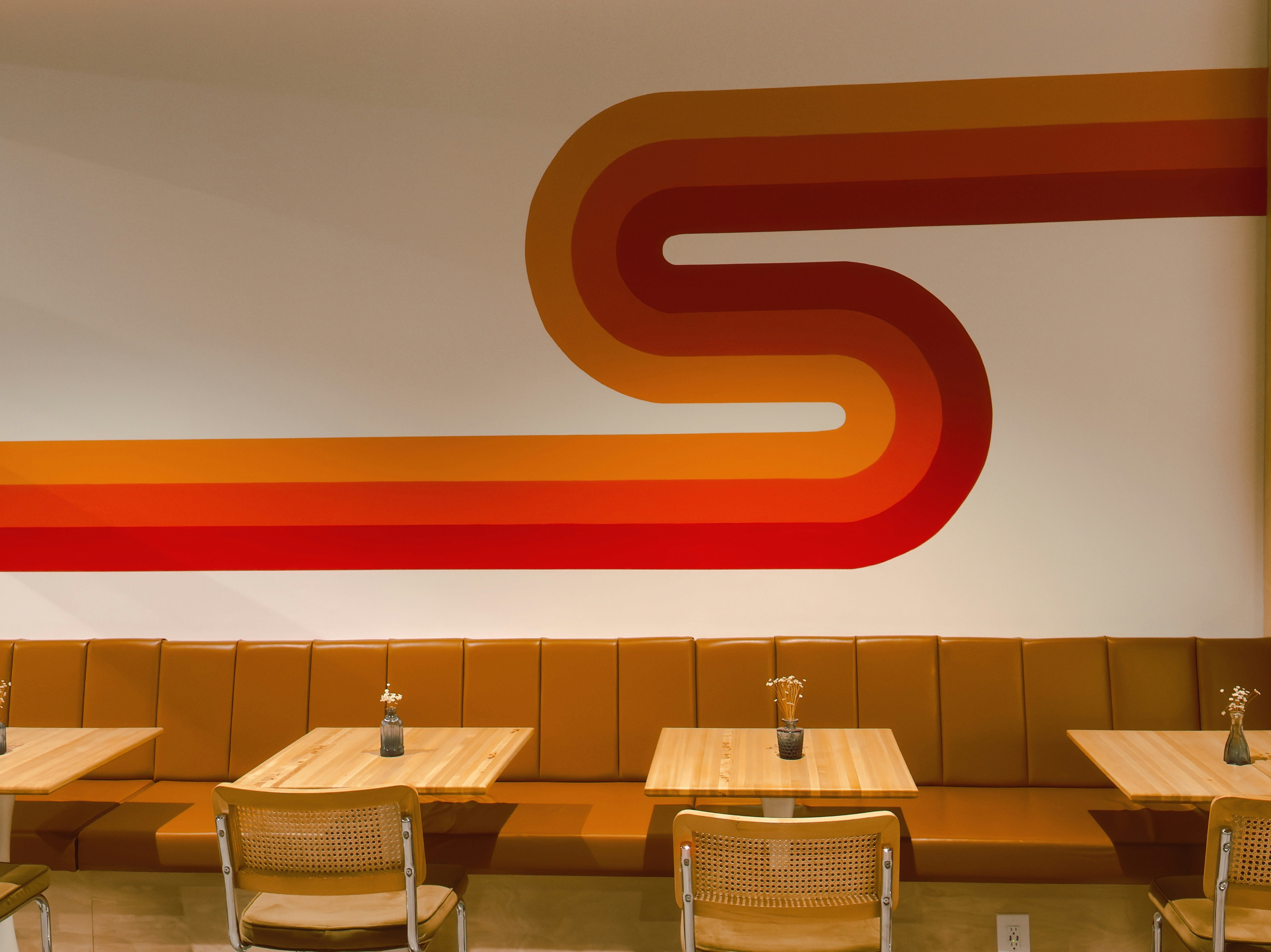 Retro wavy stripes adorn a restaurant wall above booths.