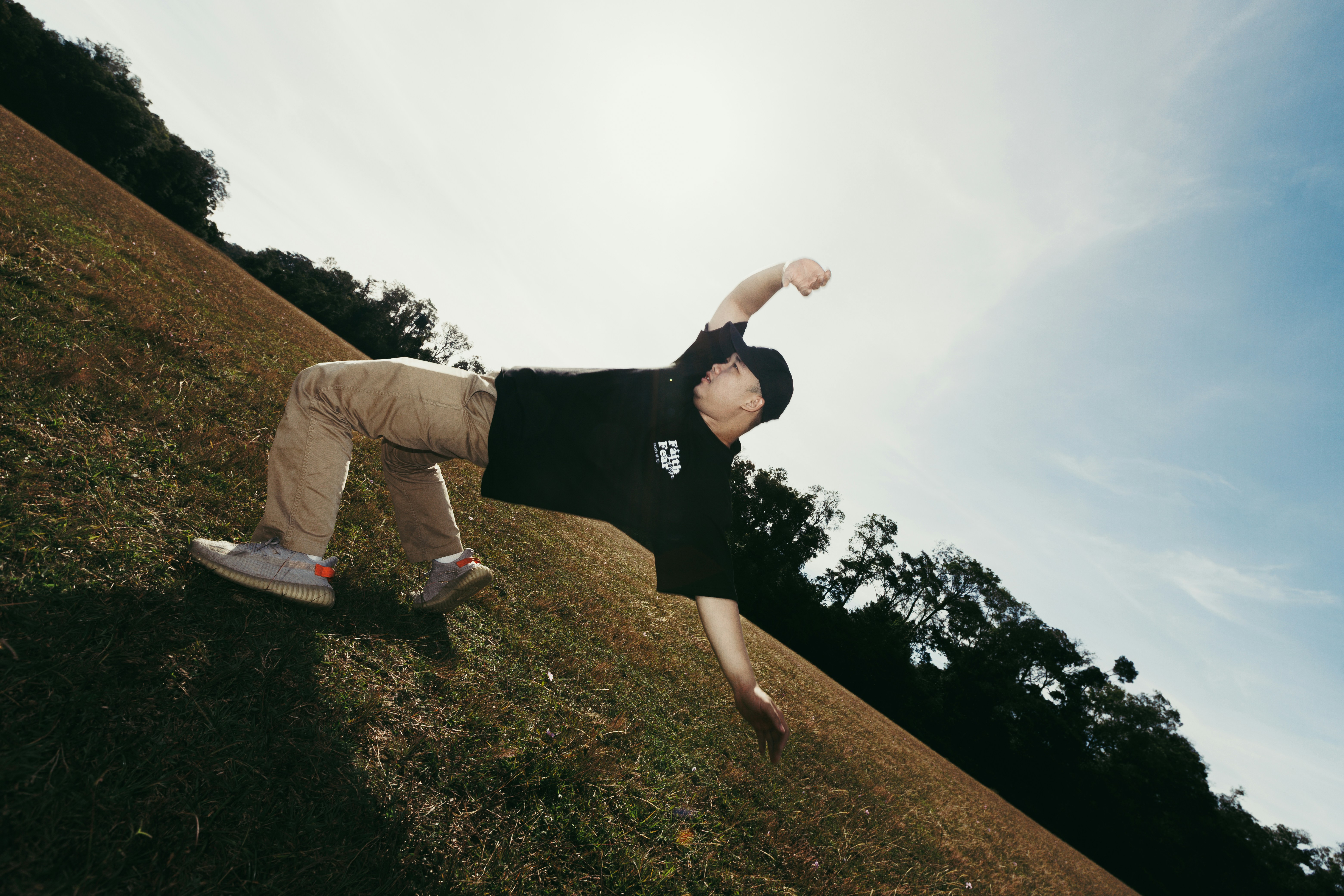 A person breakdancing on a grassy hill.
