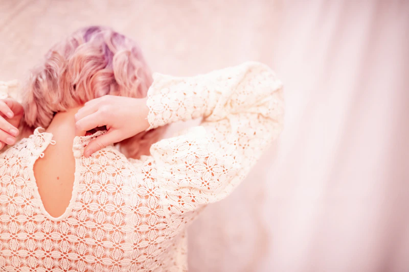 Woman with pink curly hair adjusting her top
