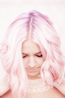Woman with wavy pink hair and a white collar