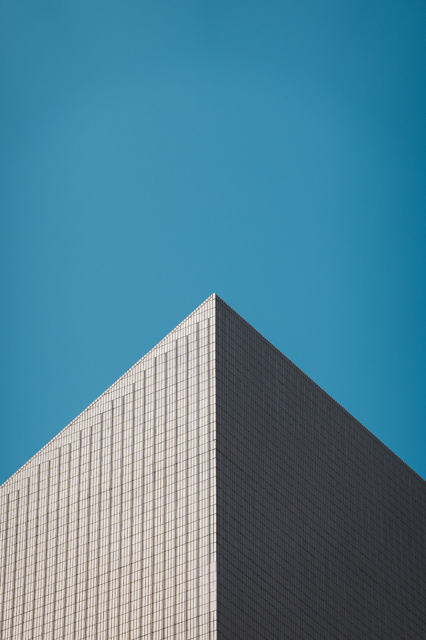 Glass facade of a modern office building against a blue sky