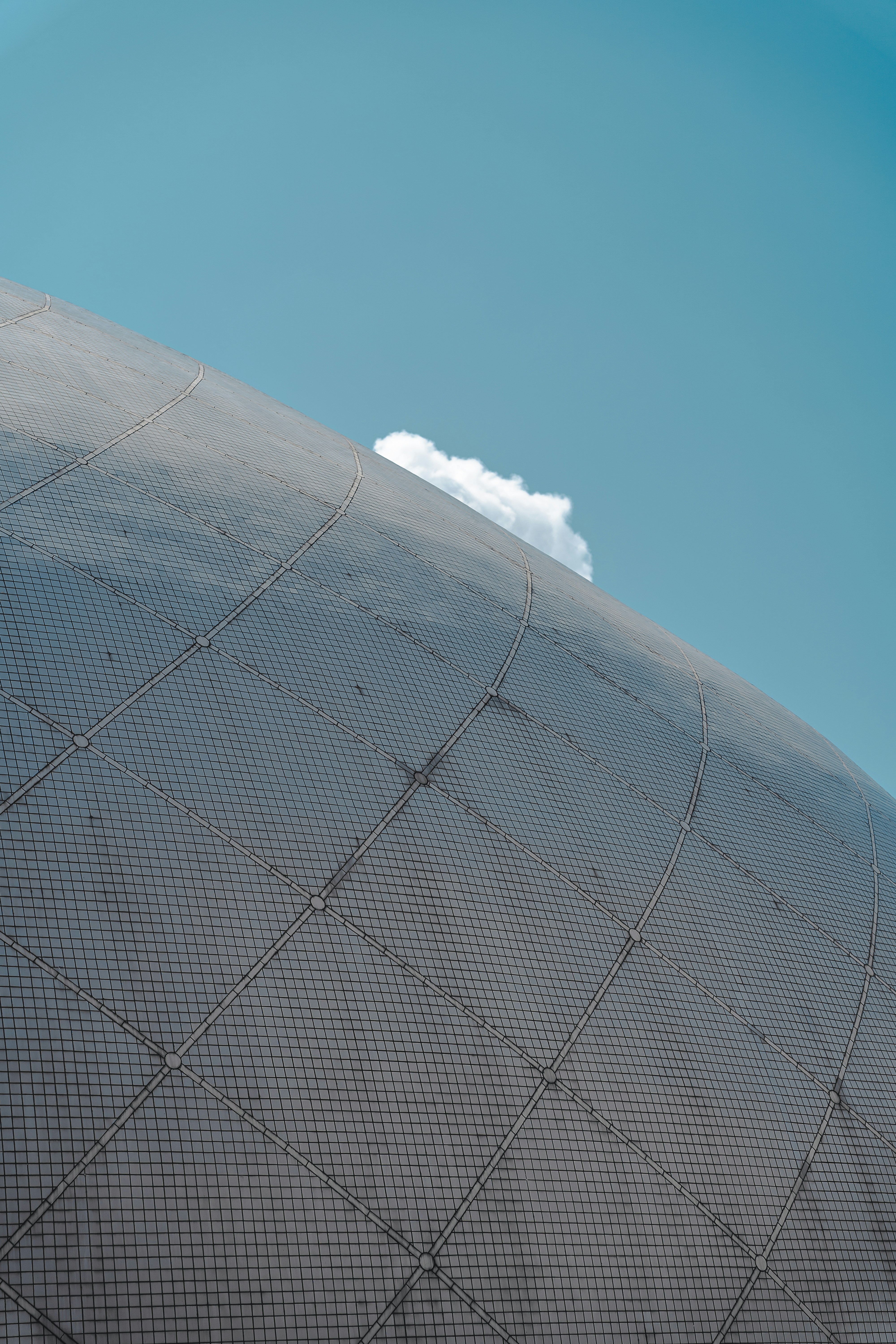 Curved metallic surface against a clear blue sky