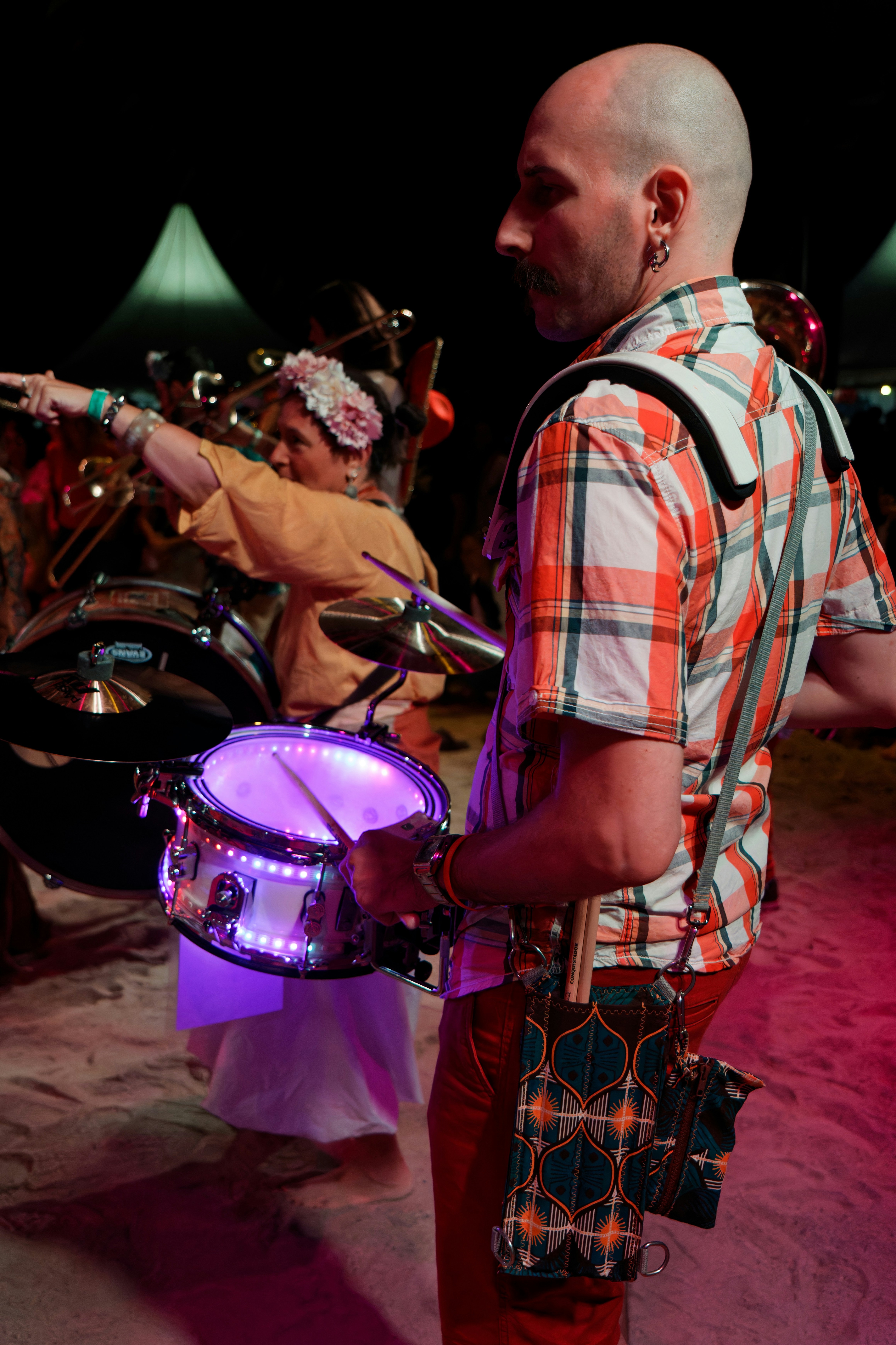 Man playing a drum with lights at a festival.