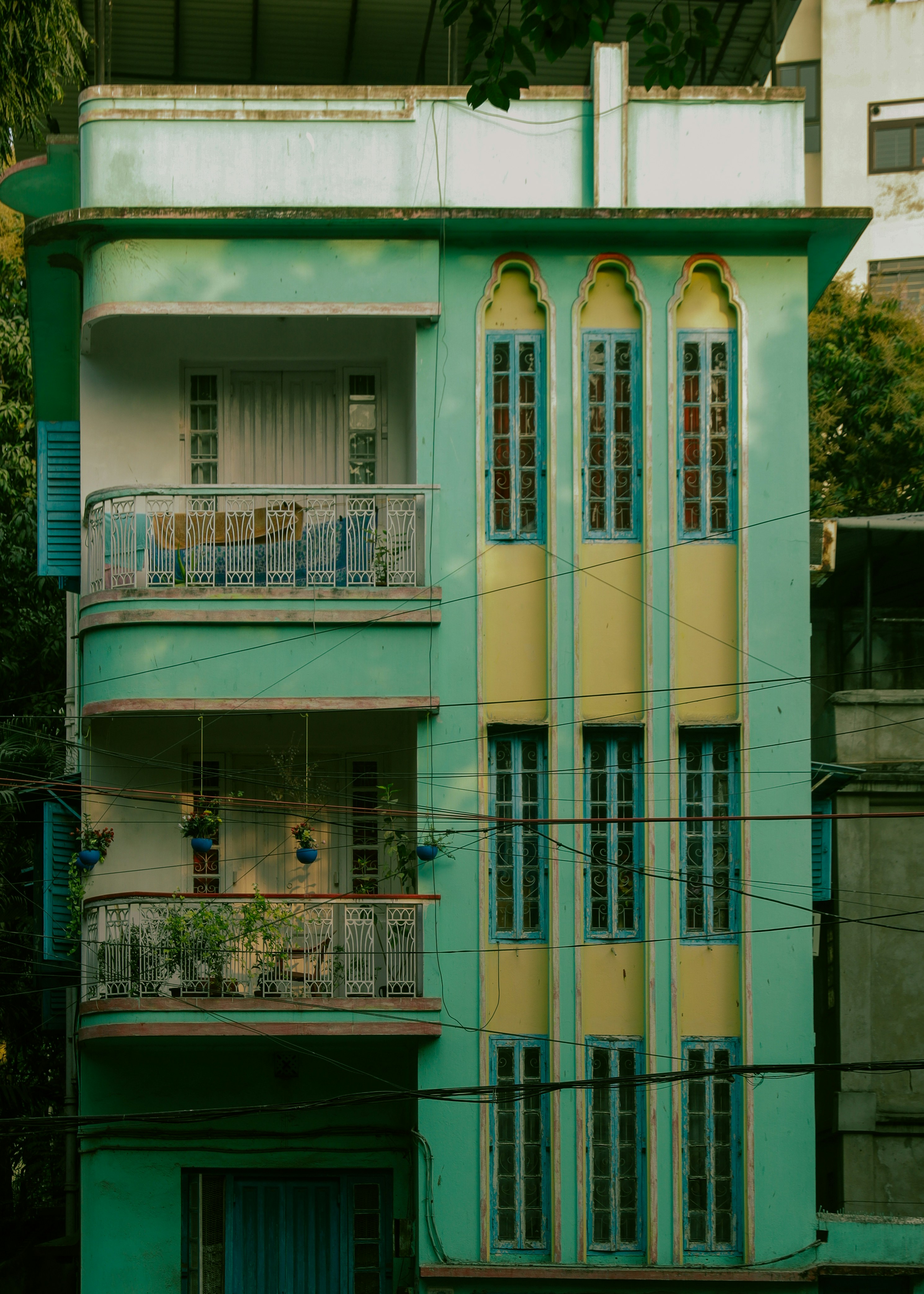 A tall, narrow, mint green building with yellow accents.