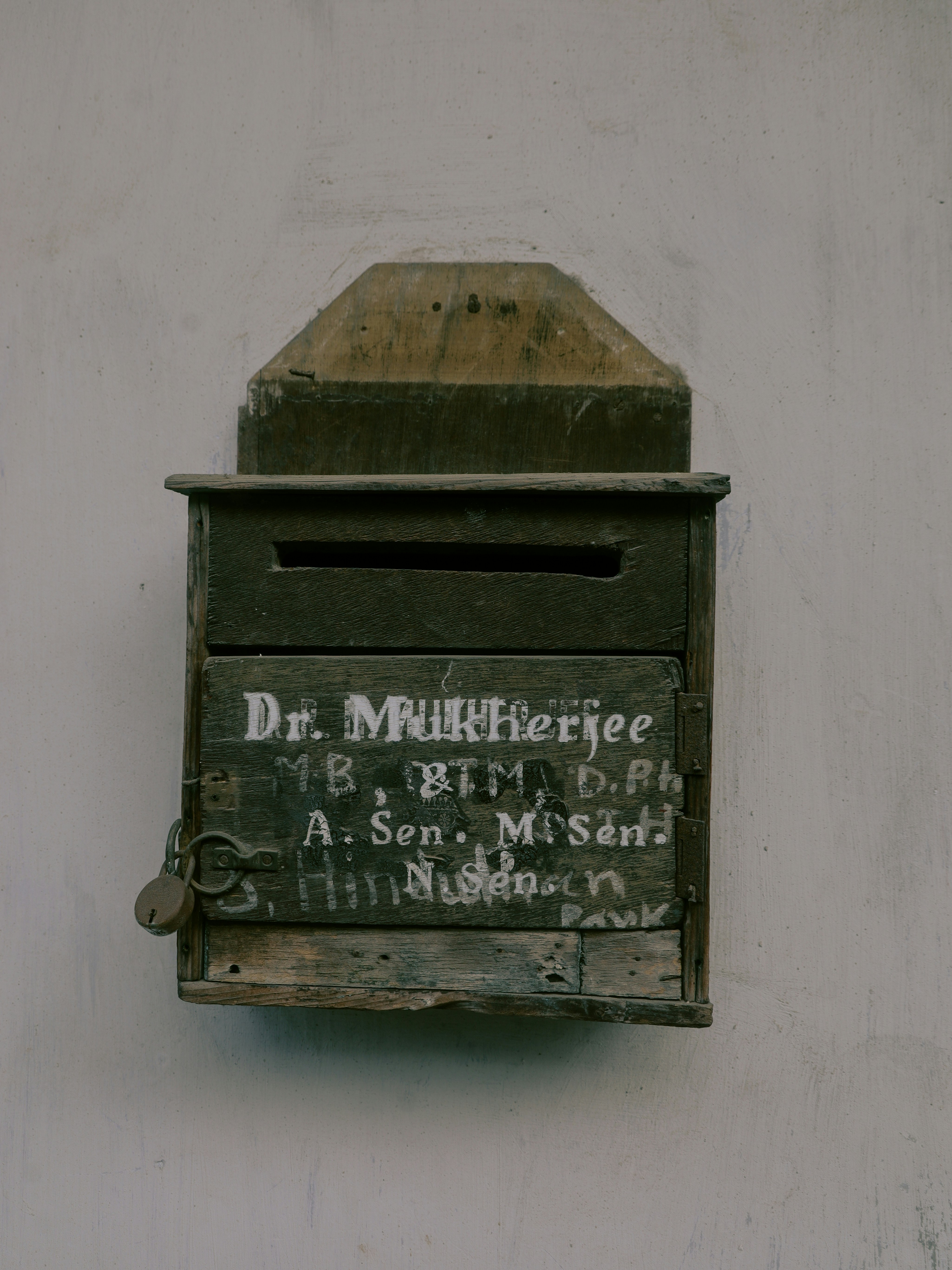 Old wooden mailbox with writing and a lock