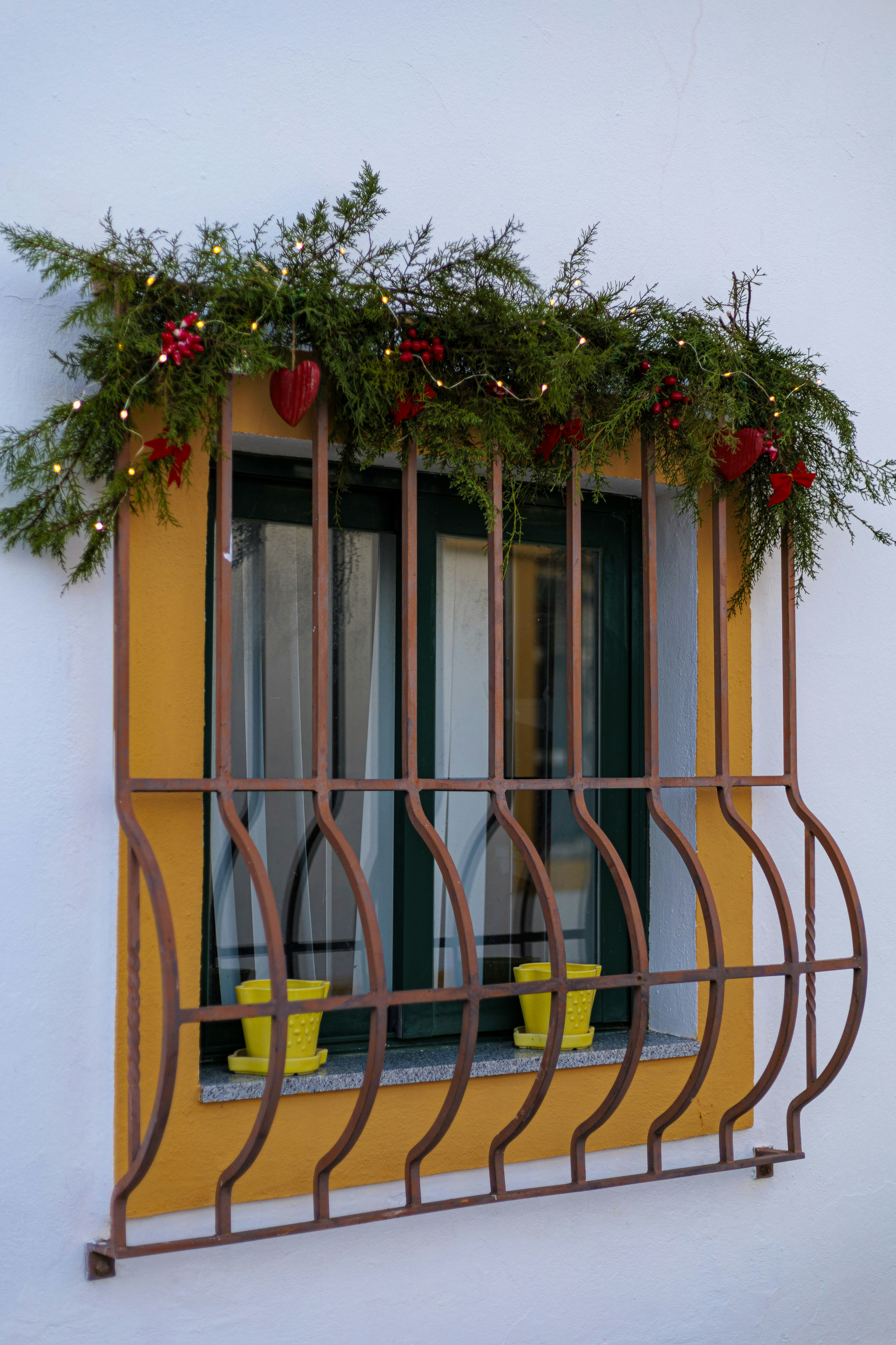 Window decorated with christmas greenery and lights.