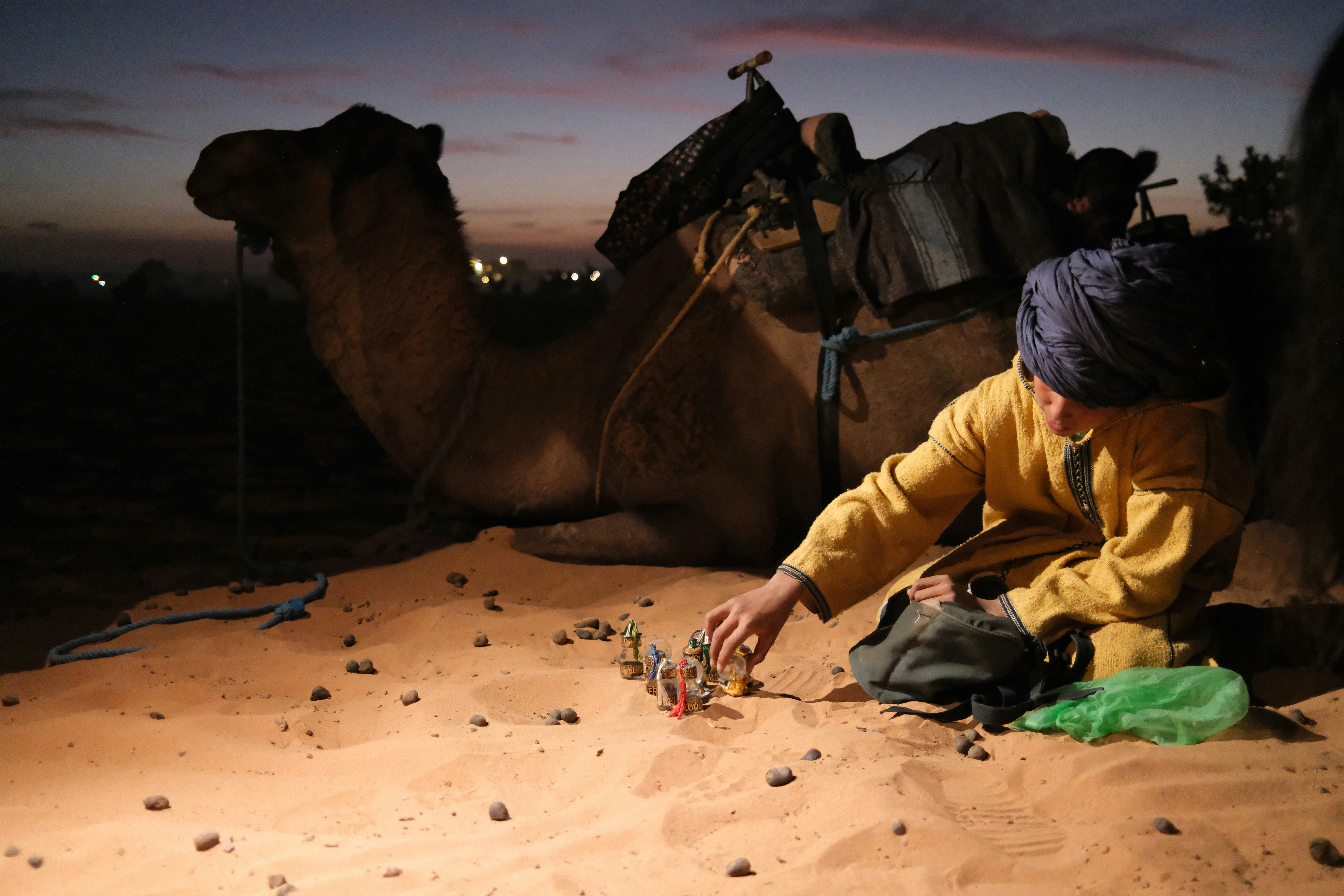 Man with camel in desert at dusk