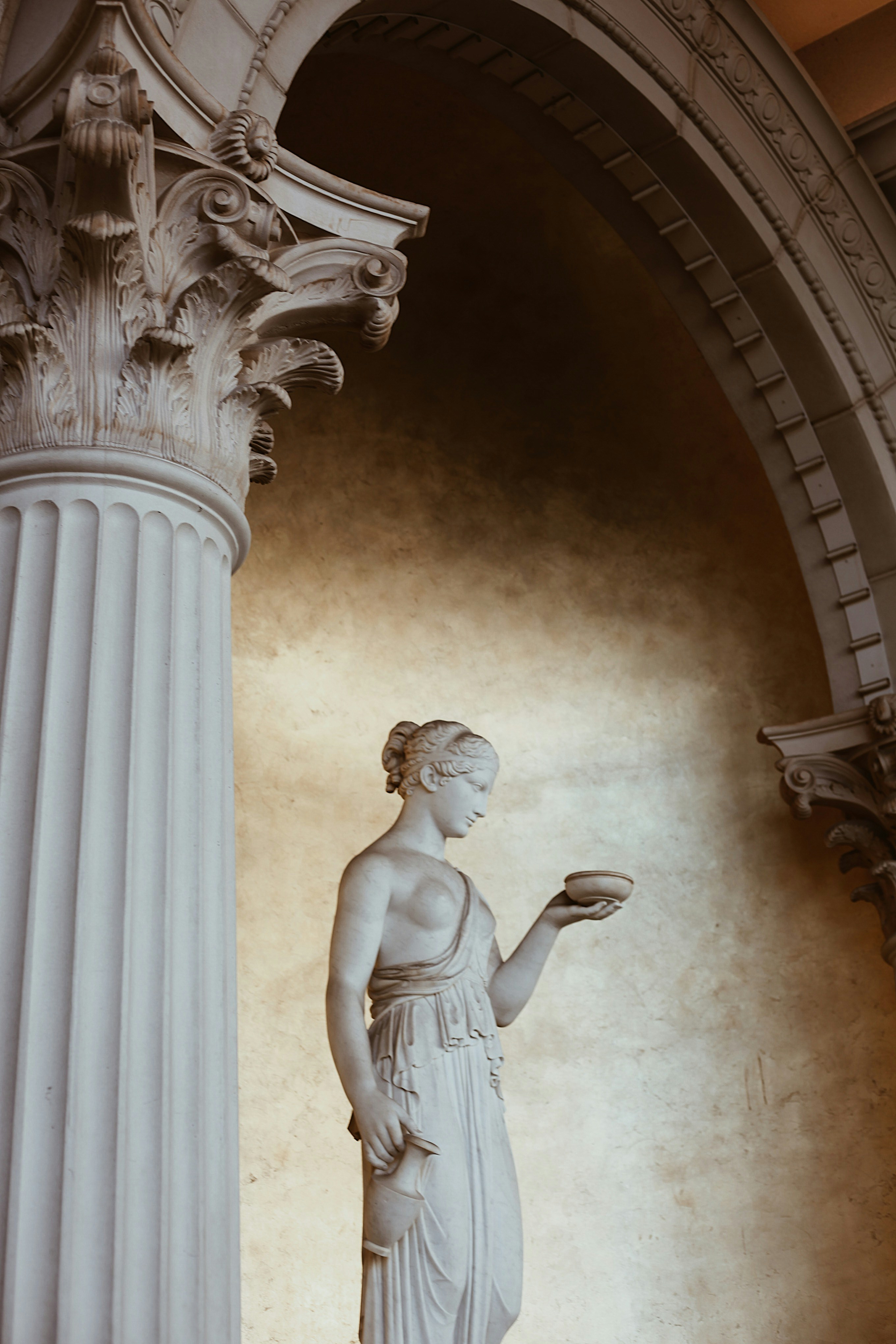 Uma estátua clássica de uma mulher segurando uma tigela.