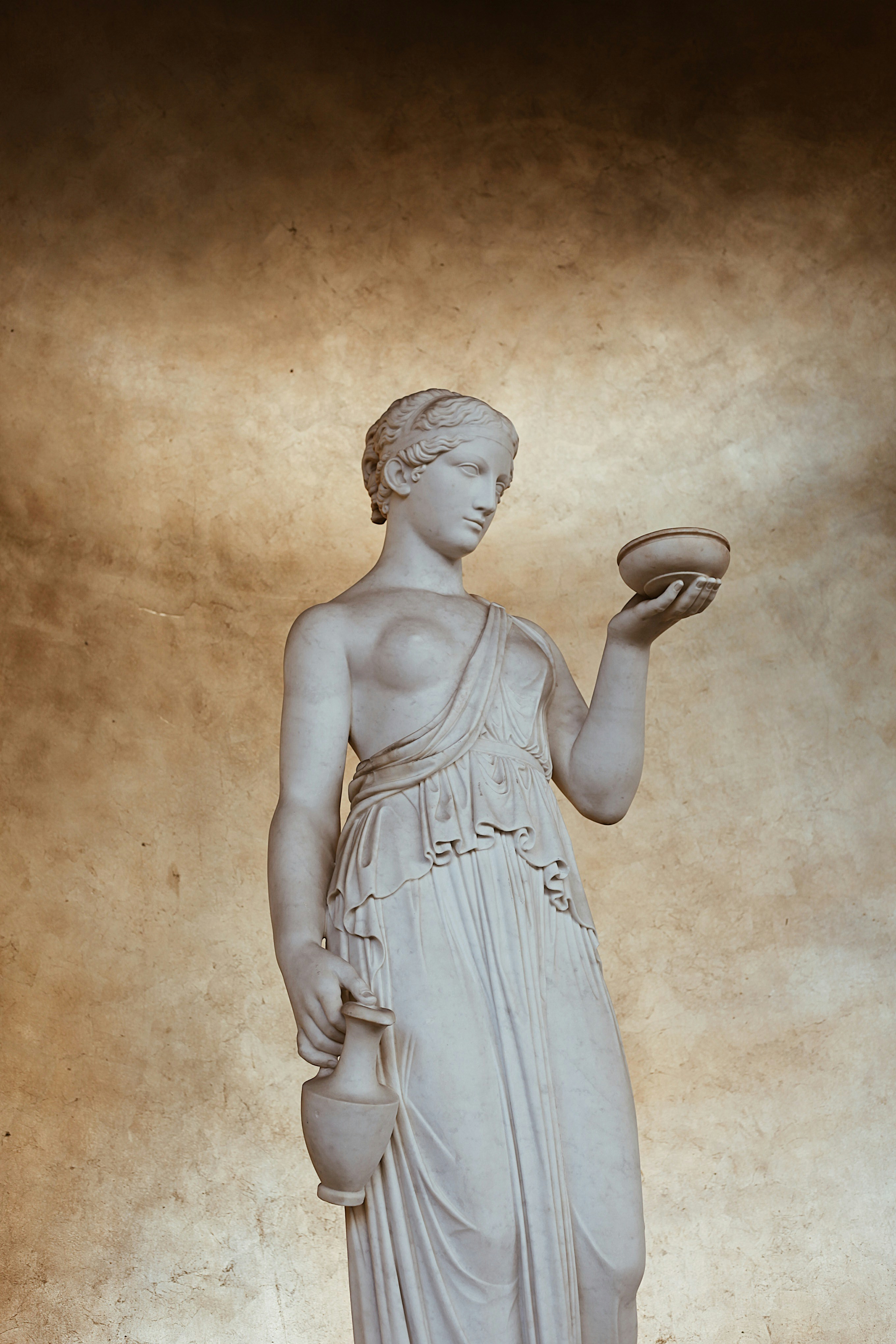 Estátua de mármore de uma mulher segurando uma tigela e um jarro